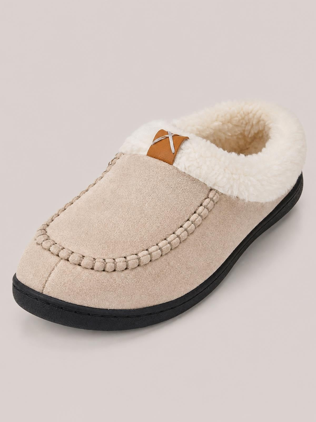 A beige round-toe flat slipper features a soft textile upper, contrast black TPR sole, fluffy lining, and stitched moccasin-style trim.