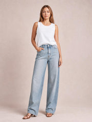 Model wearing light blue contrast straight-leg jeans with front pockets, a high waist, button closure, and wide full-length legs, posed with one hand in a pocket.
