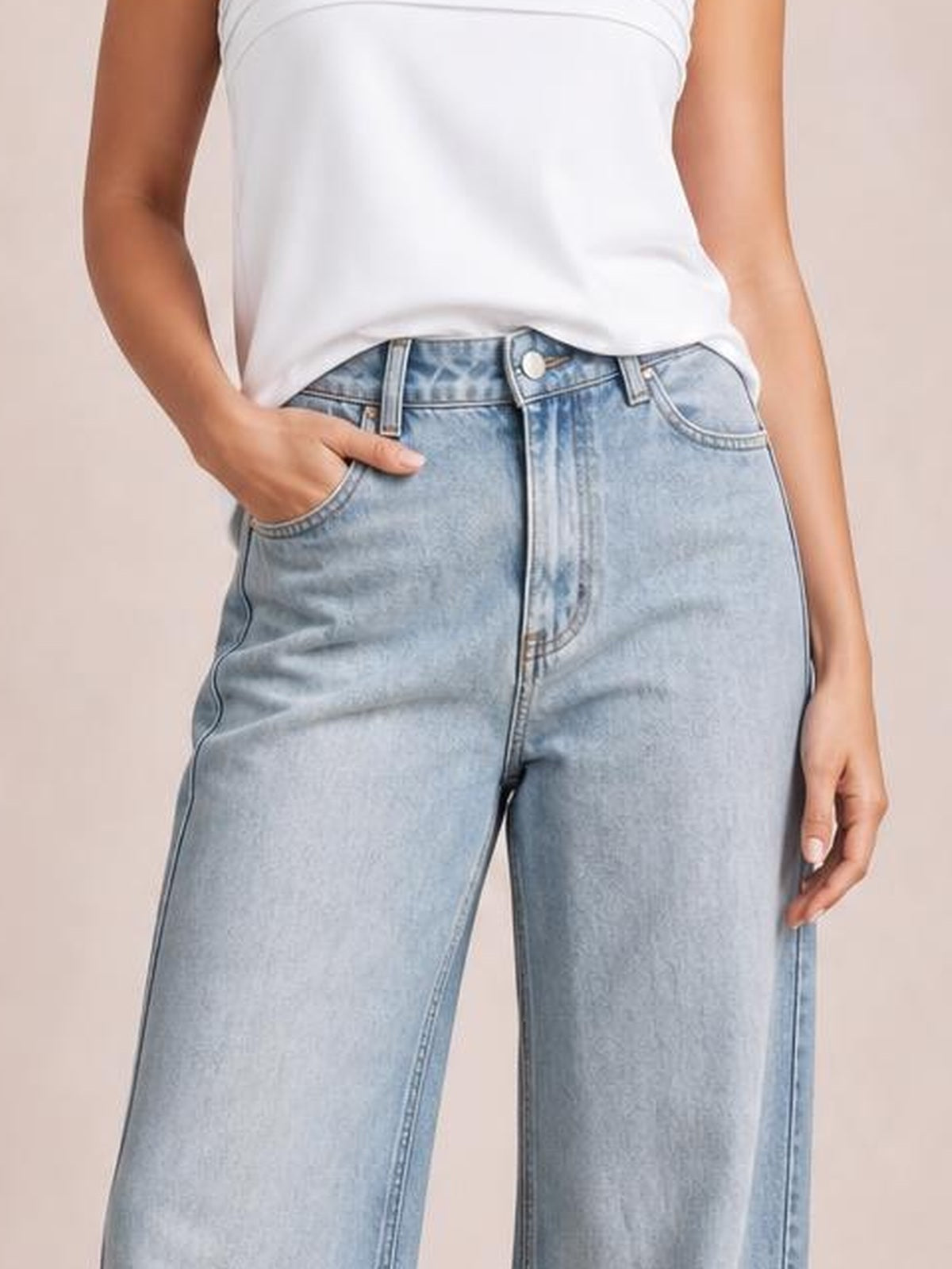 Model wearing light blue straight-leg jeans with contrast stitching, belt loops, button closure, front pockets, and a hand resting in one pocket.