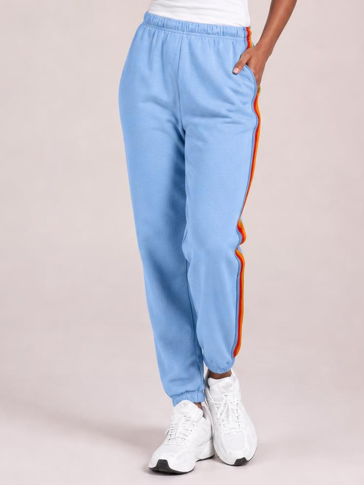 Model wearing light blue contrast striped elastic waist active pants with a relaxed jogger silhouette, side pockets, and cuffed ankles.