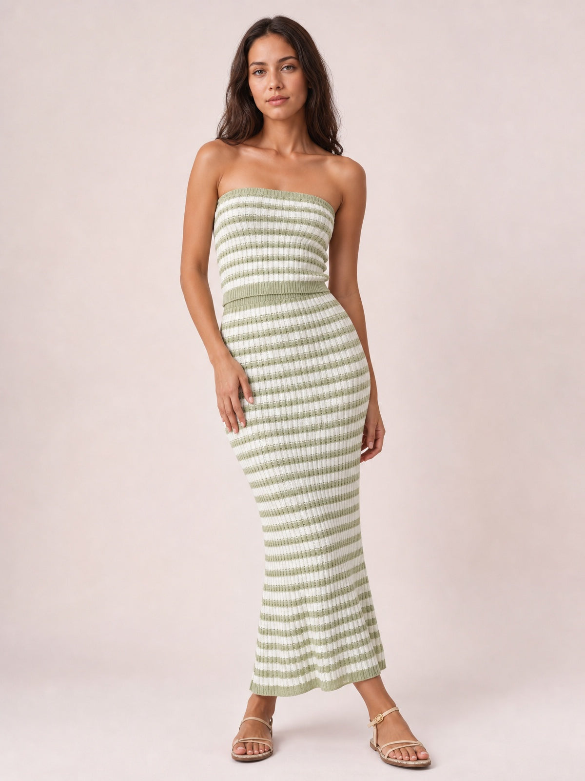 Model poses in a green and white striped sweater-style dress with a strapless tube top, fitted silhouette, defined waistband, and sleek midi-length skirt.