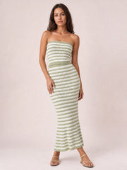 Model poses in a green and white striped sweater-style dress with a strapless tube top, fitted silhouette, defined waistband, and sleek midi-length skirt.