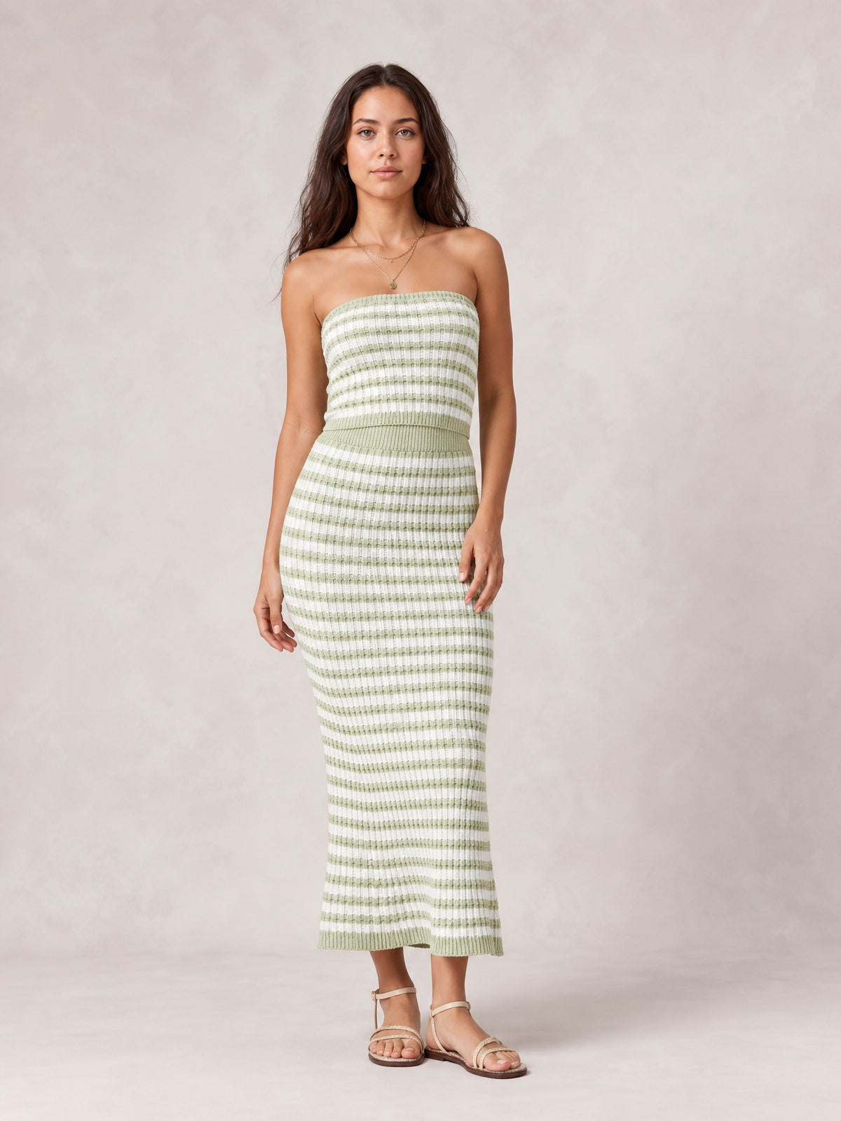 Model poses in a green-and-white striped sweater-style dress with a strapless tube top, fitted silhouette, and straight midi-length skirt.