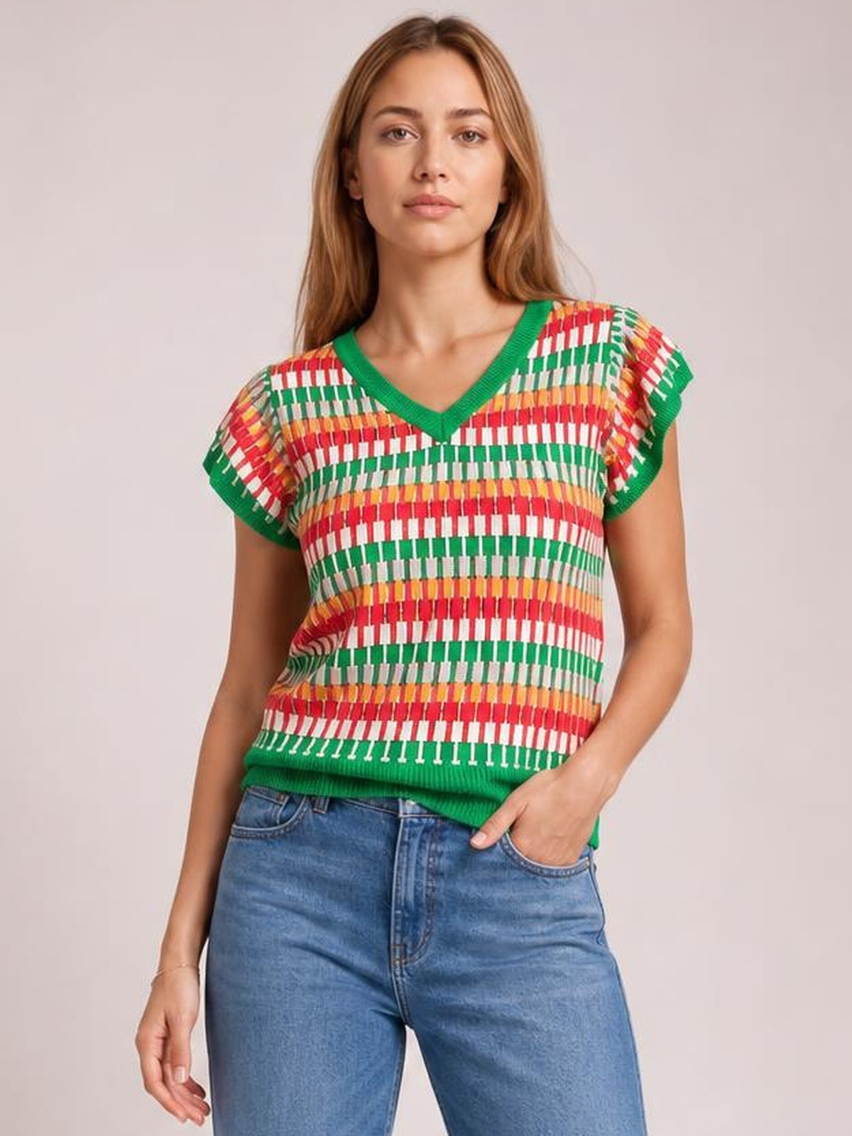 A model stands in a relaxed pose wearing a colorful contrast-striped V-neck knit top with green ribbed trim, short sleeves, and a relaxed silhouette.