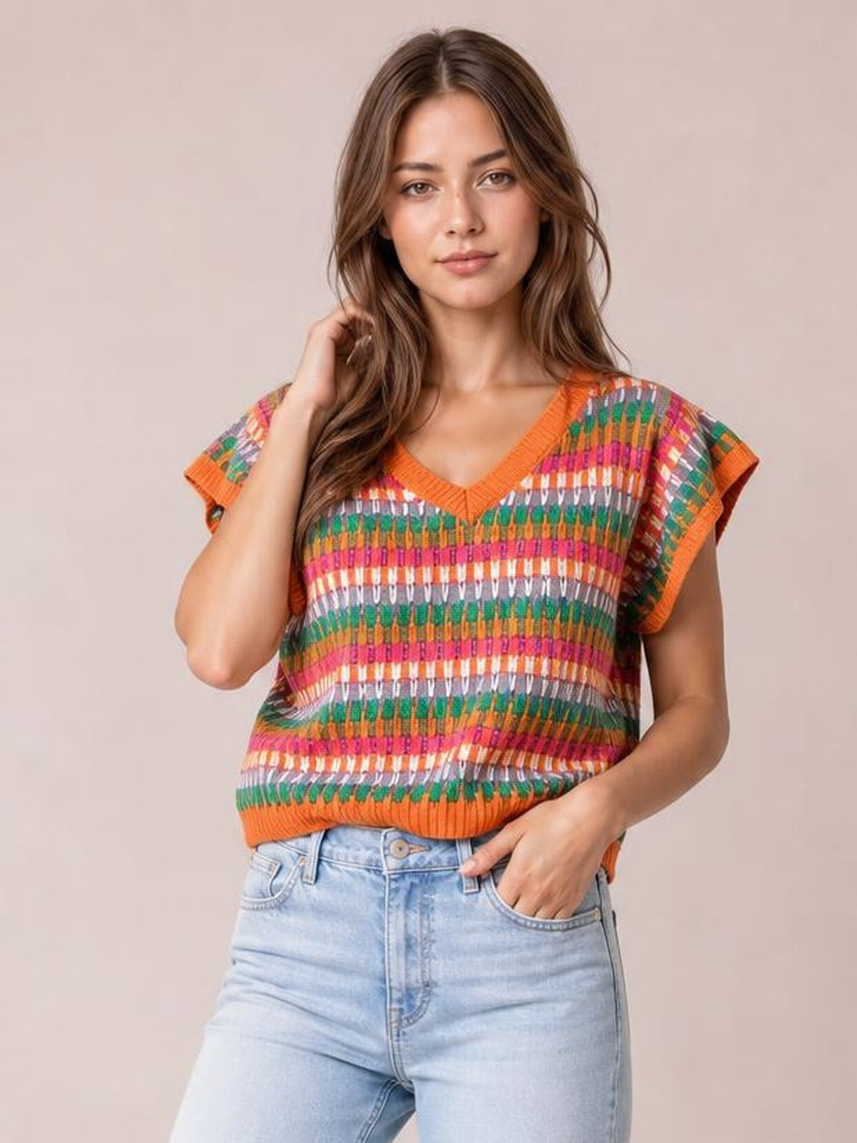 Model poses in a multicolored contrast striped knit top with an orange V-neck, ribbed trim, short sleeves, and a relaxed silhouette.