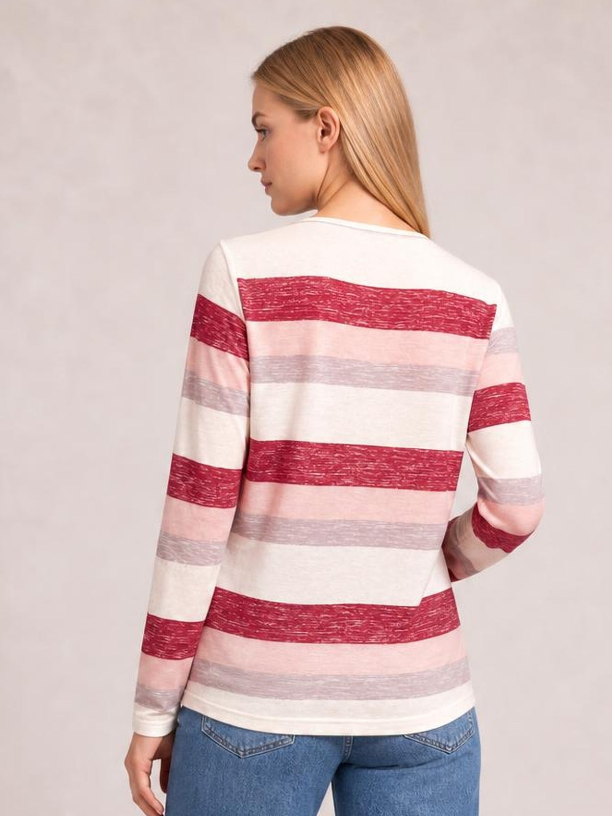 Model shown from behind wearing a contrast striped long-sleeve T-shirt in white, red, pink, and gray with a relaxed silhouette and rounded hem.