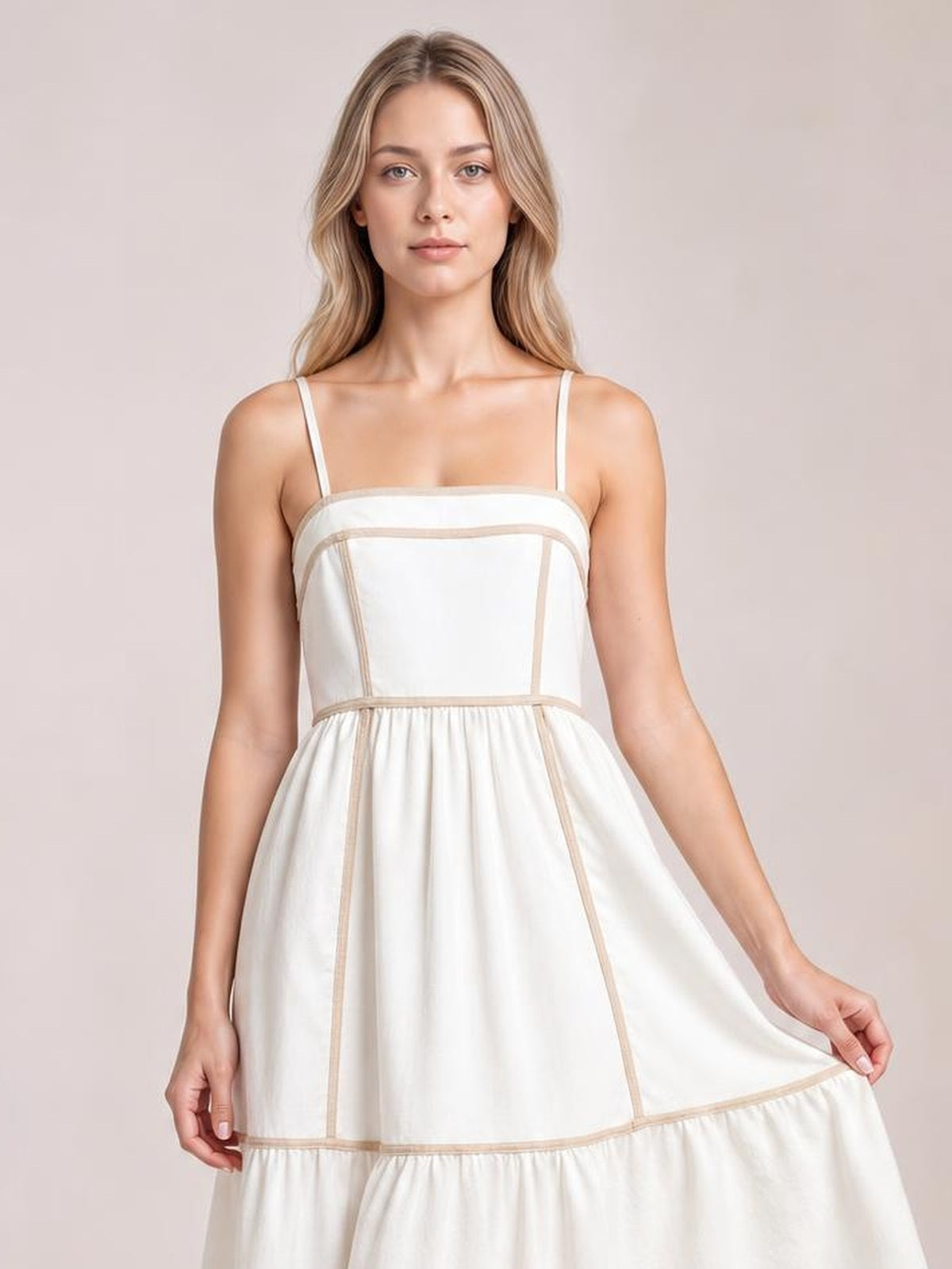 Model holds the skirt sides of a white square-neck midi cami dress with thin straps, contrast trim, a fitted bodice, and a softly gathered tiered silhouette.