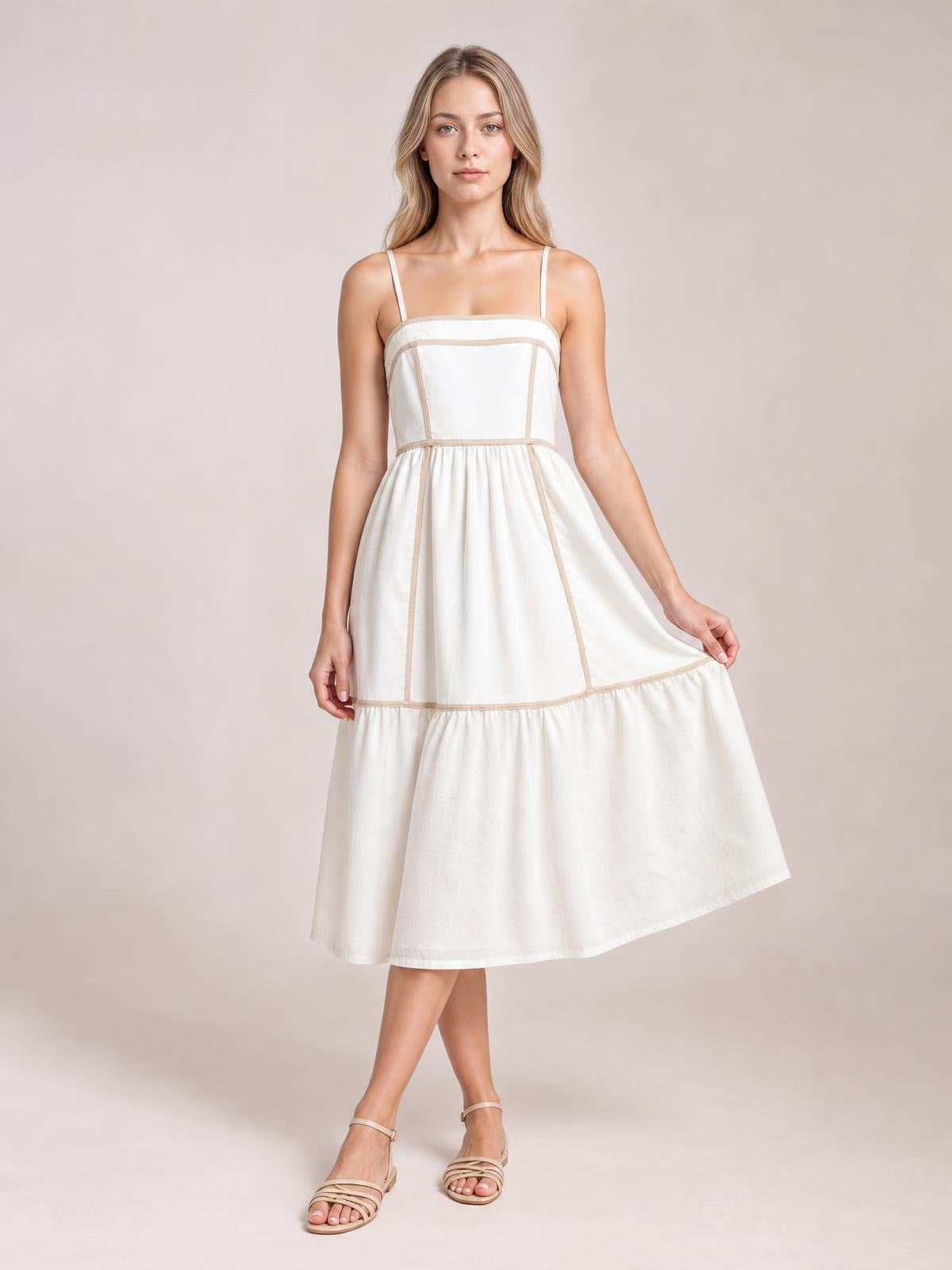 A model wears an ivory contrast-trim square-neck midi cami dress with slim straps, a paneled bodice, gathered waist, and flared tiered skirt.