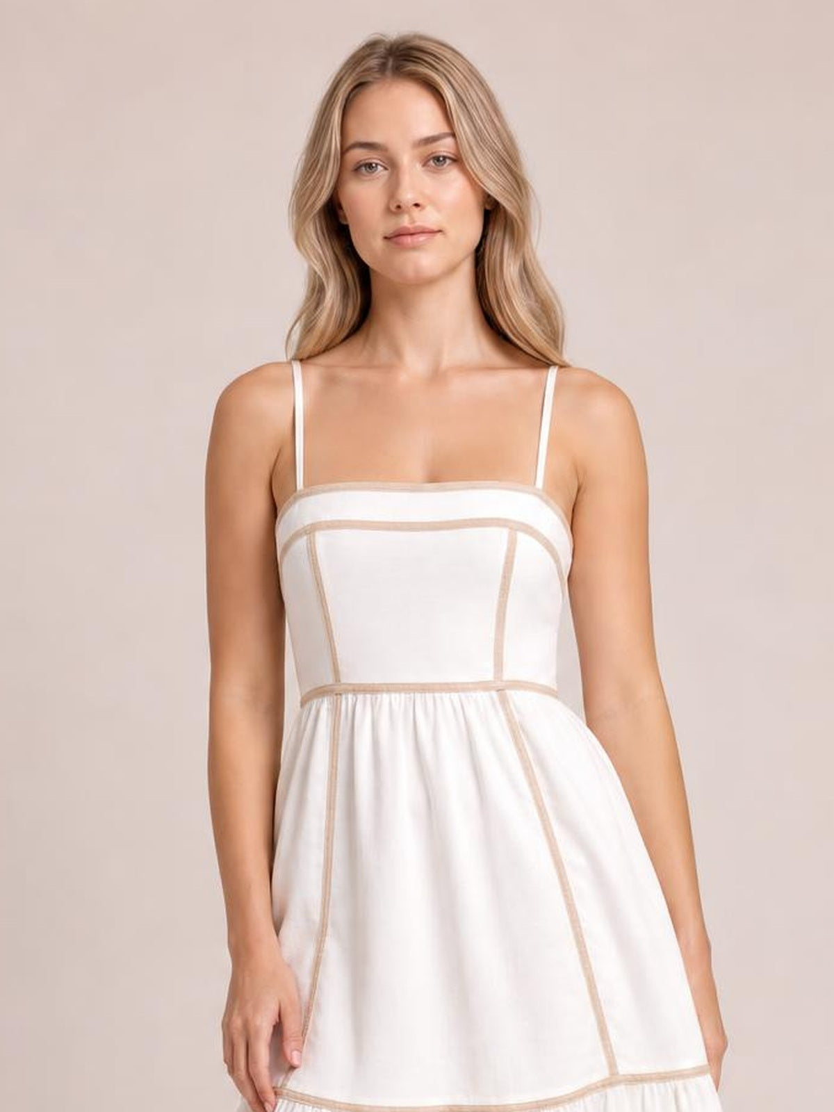 A model stands facing forward in a white square-neck midi cami dress with thin straps, contrast trim, a fitted bodice, ruched waist, and flared skirt.