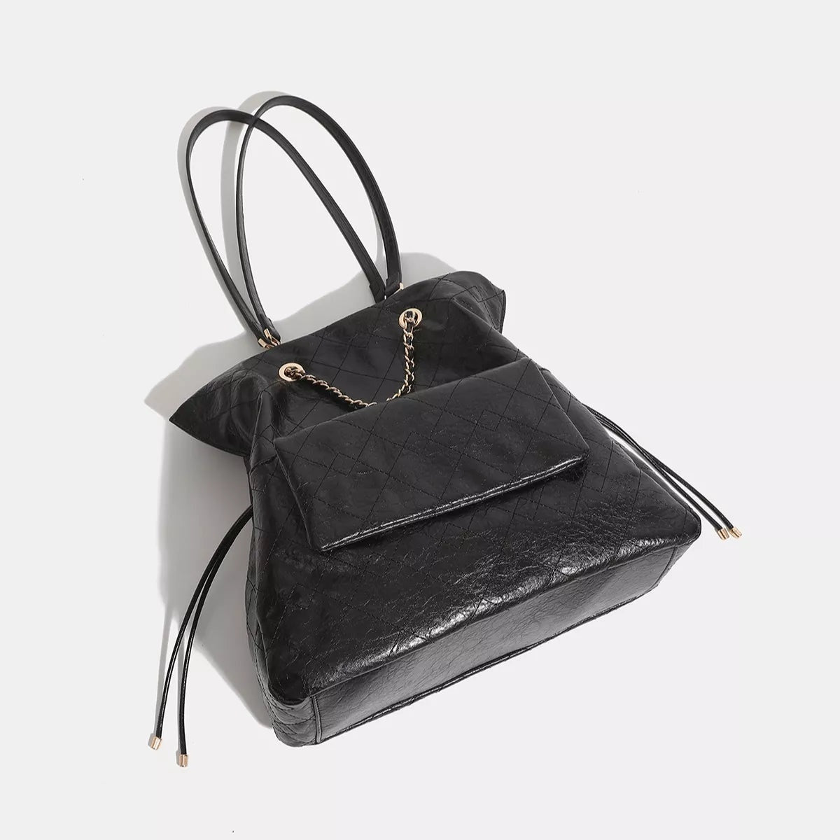 Large black PU leather convertible drawstring backpack with a quilted texture, structured silhouette, flap pocket, long straps, and gold-tone chain detail.
