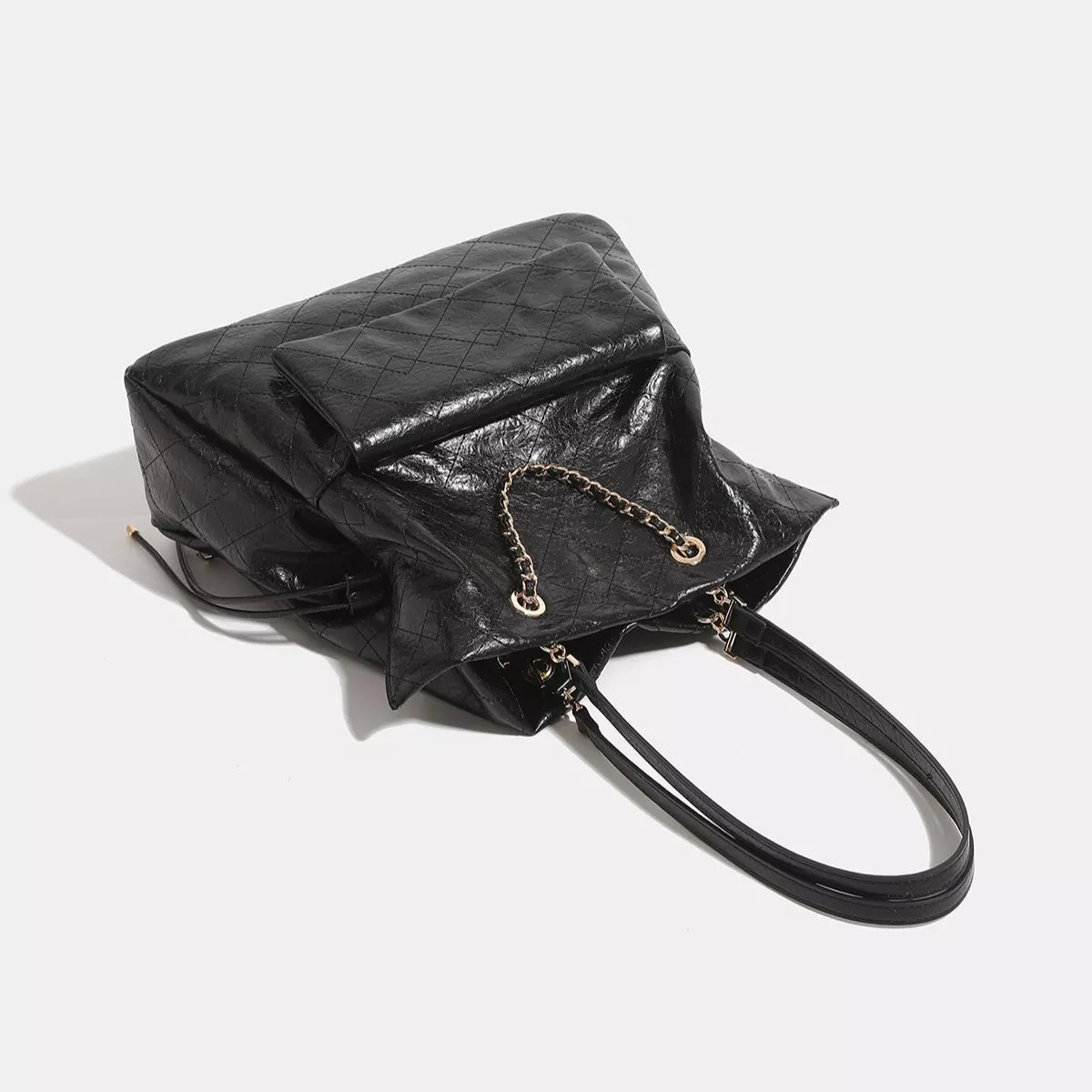 Large black quilted PU leather convertible drawstring backpack bag with a flap closure, chain detailing, and long adjustable straps.