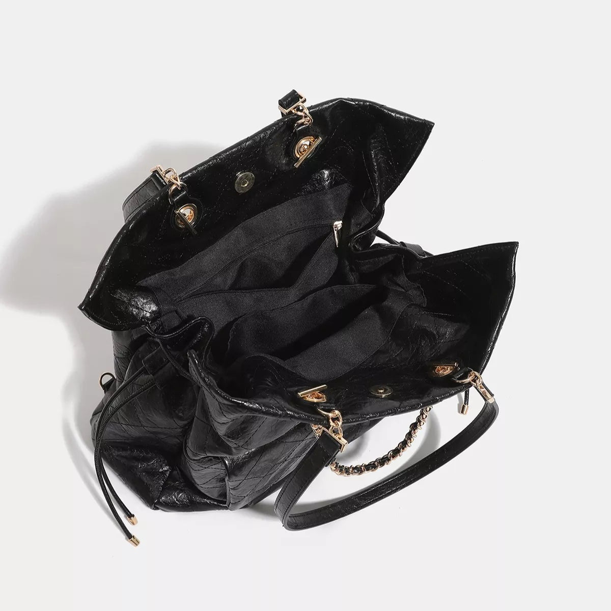 Large black PU leather convertible drawstring backpack bag shown open, revealing a zippered interior pocket, multiple straps, and gold-tone hardware.