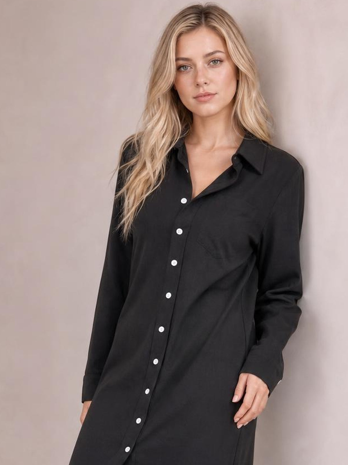 A model wears a black corduroy shirt dress with a collared button-down front, long sleeves, relaxed straight silhouette, and side pockets.