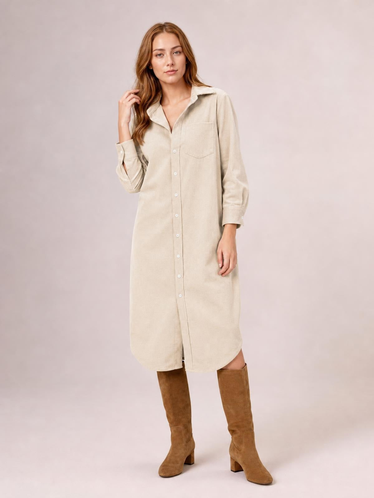 A model poses in a beige corduroy shirt dress with a button-down front, pointed collar, long sleeves, chest pocket, and relaxed midi-length silhouette.