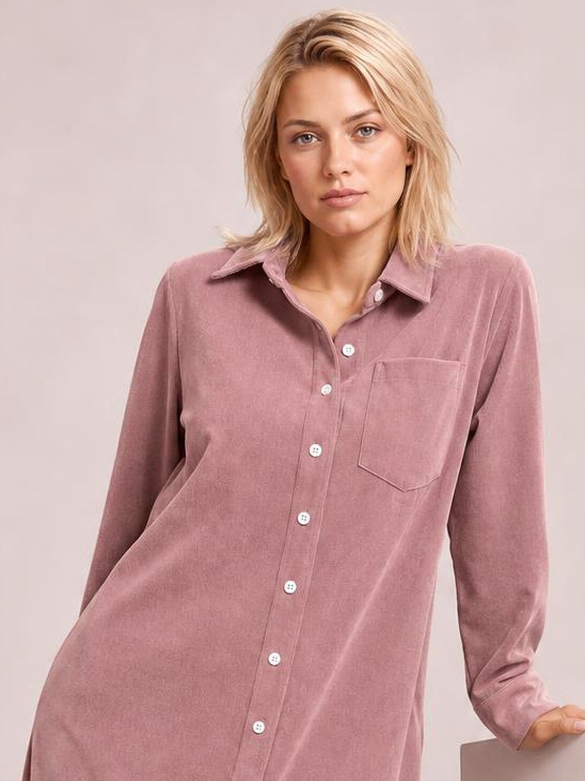 A woman models a dusty rose corduroy shirt dress with a relaxed silhouette, pointed collar, long sleeves, button-down front, and chest pocket.