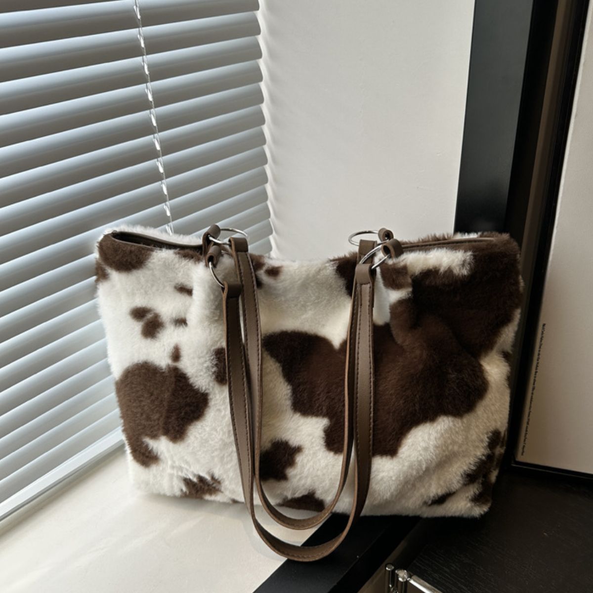 Cow print furry tote bag in a large rectangular silhouette with soft white and brown faux fur, contrasting PU leather trim, and long shoulder straps.