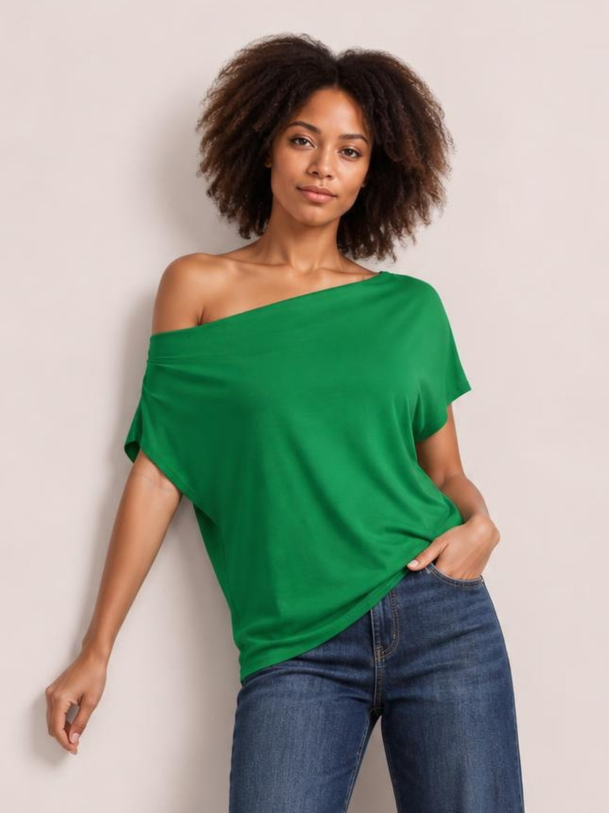 Model poses in a green cowl neck short sleeve T-shirt with a loose, draped silhouette and wide neckline.