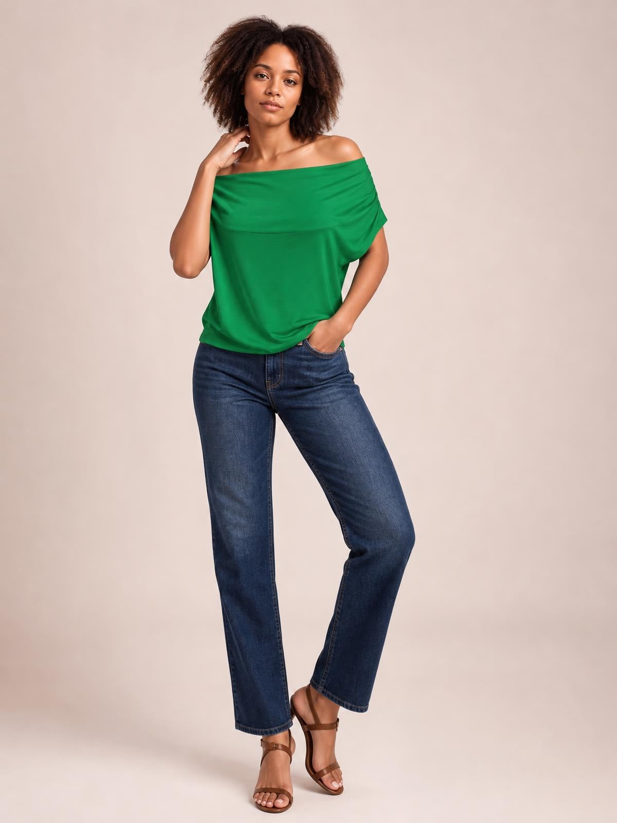 Model wearing a green cowl neck short sleeve T-shirt with a softly draped, relaxed silhouette and wide neckline, posing with one hand at her neck.