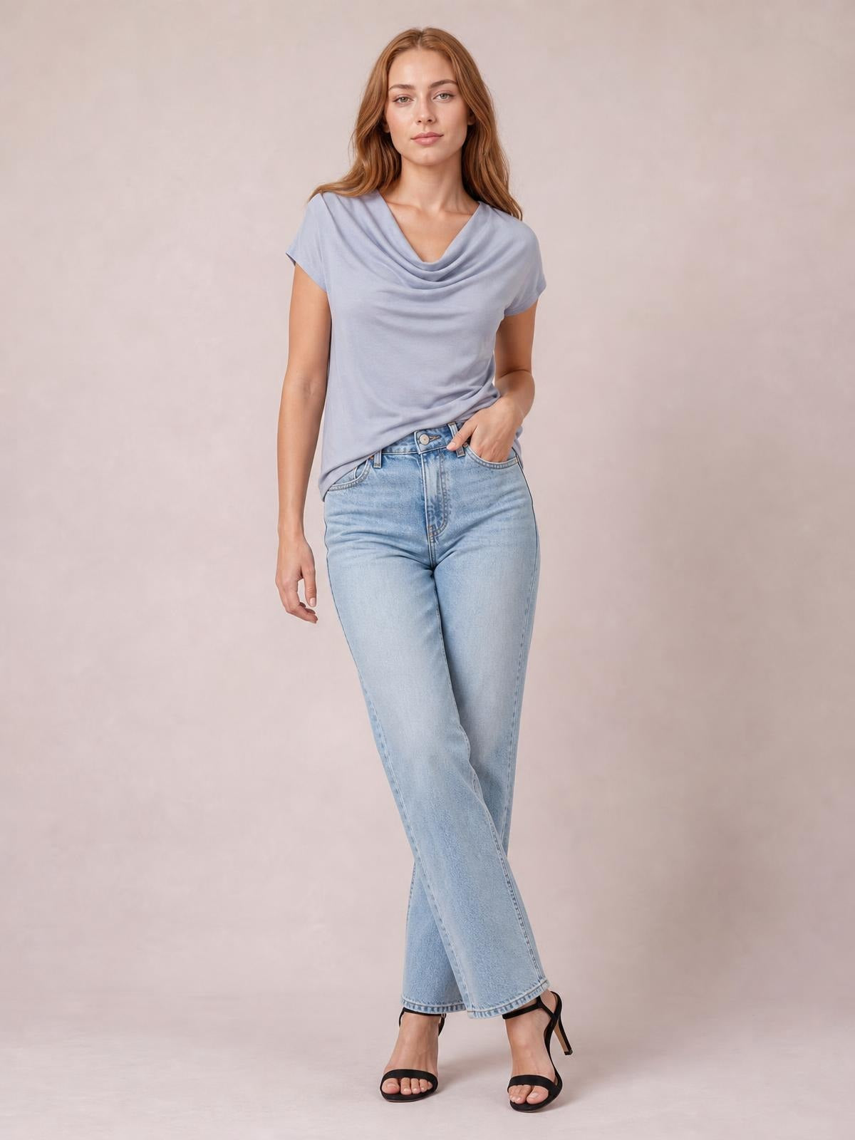 Model poses in a light lavender cowl neck short sleeve T-shirt with a softly draped neckline and relaxed straight silhouette, paired with jeans.
