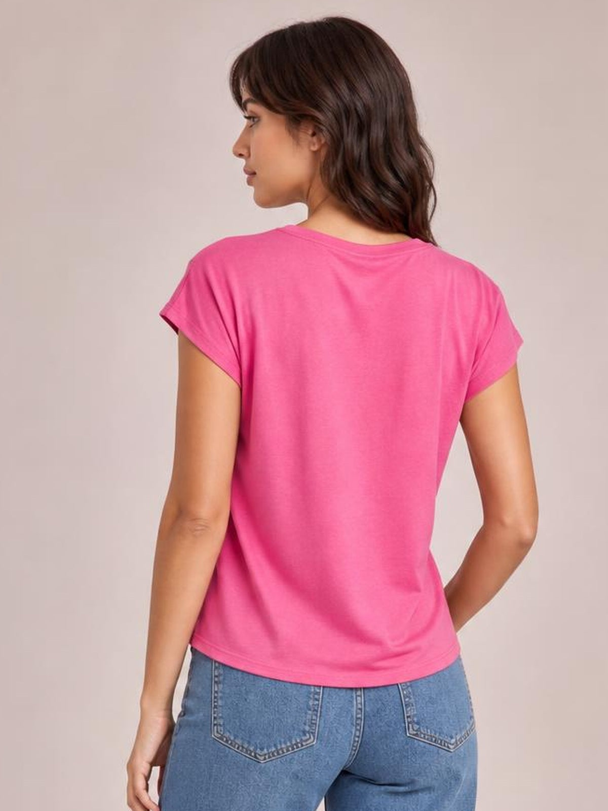 Model shown from behind in a bright pink cowl neck short sleeve T-shirt with a relaxed silhouette, simple construction, and straight hem.