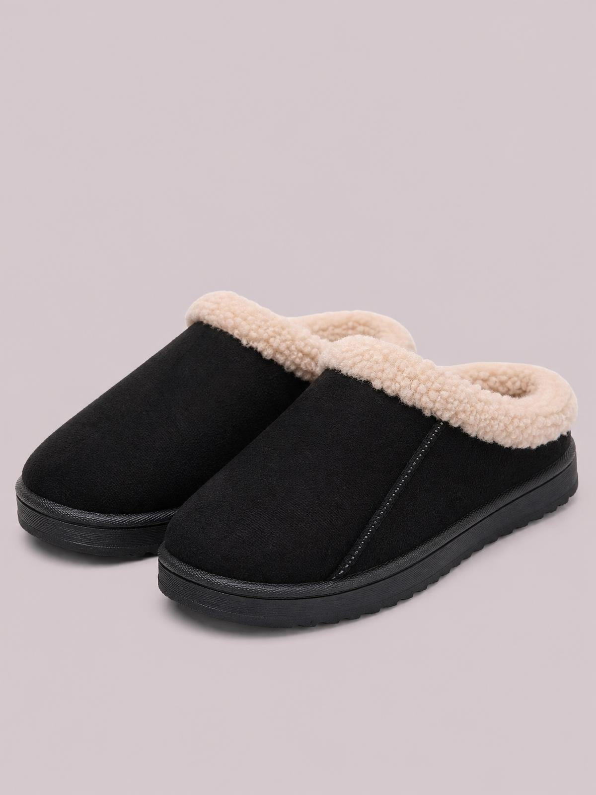 Black suede slippers with cozy cream faux fur lining, slip-on mule silhouette, low flat soles, and neat side seam construction.
