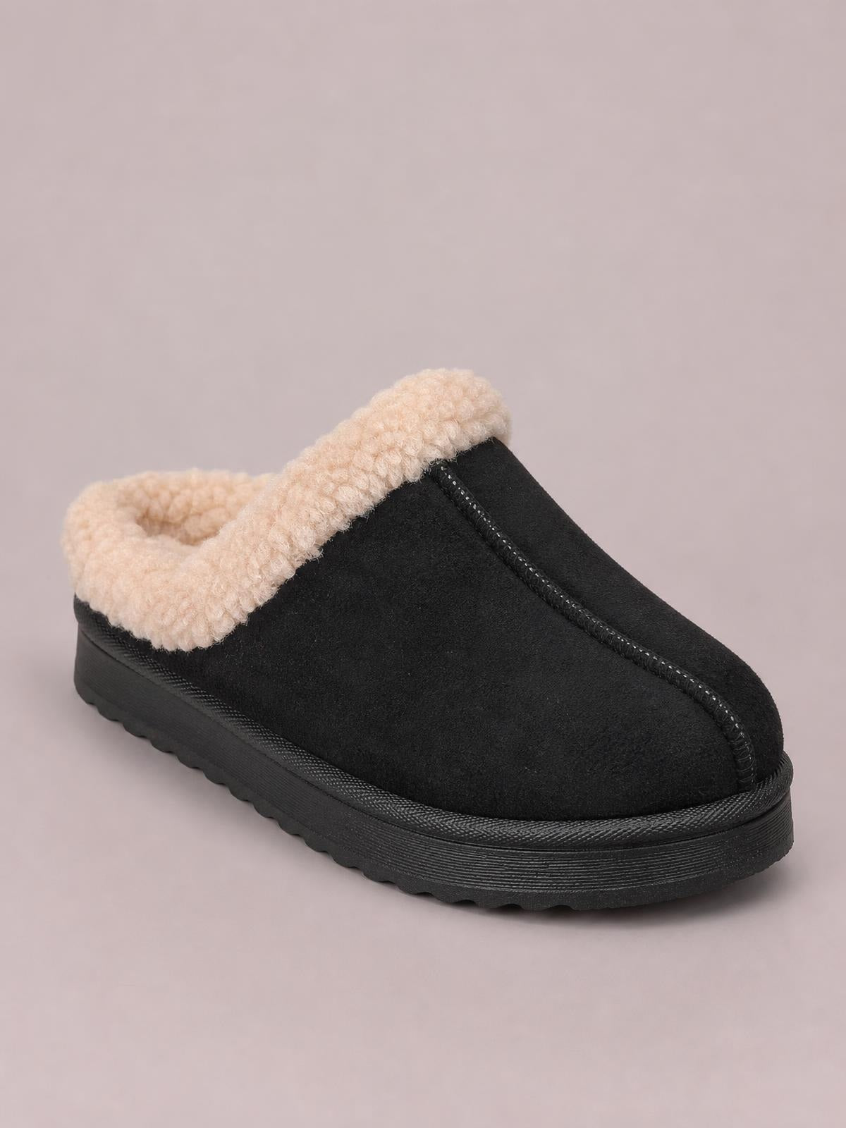 Black faux suede slippers feature a closed-toe silhouette, cozy cream faux fur lining, stitched front seam, and a flat textured sole.