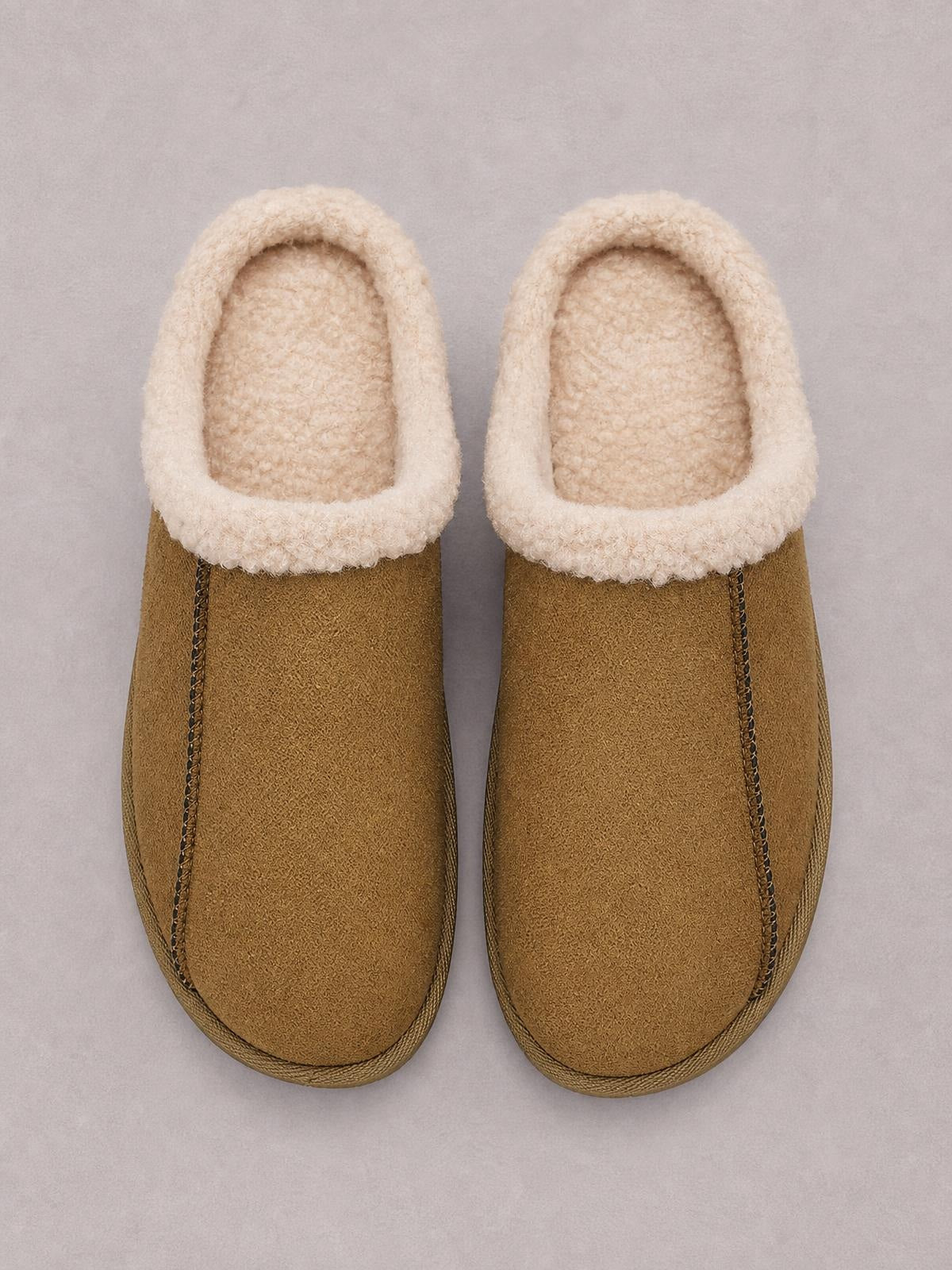 Brown suede slippers feature cozy cream faux fur lining, rounded toes, flat soles, and visible stitched panel construction.