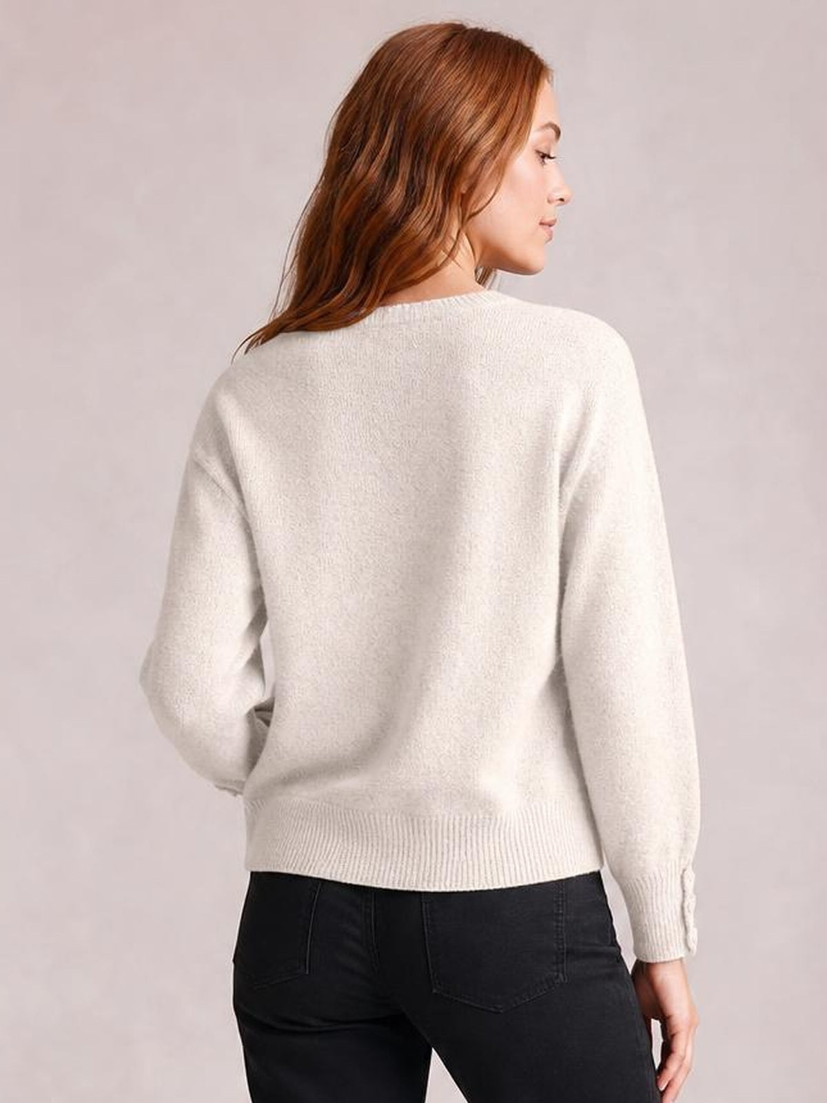 Model shown from behind wearing a cream crew neck long sleeve sweater with a relaxed silhouette, ribbed cuffs and hem, and slightly dropped shoulders.