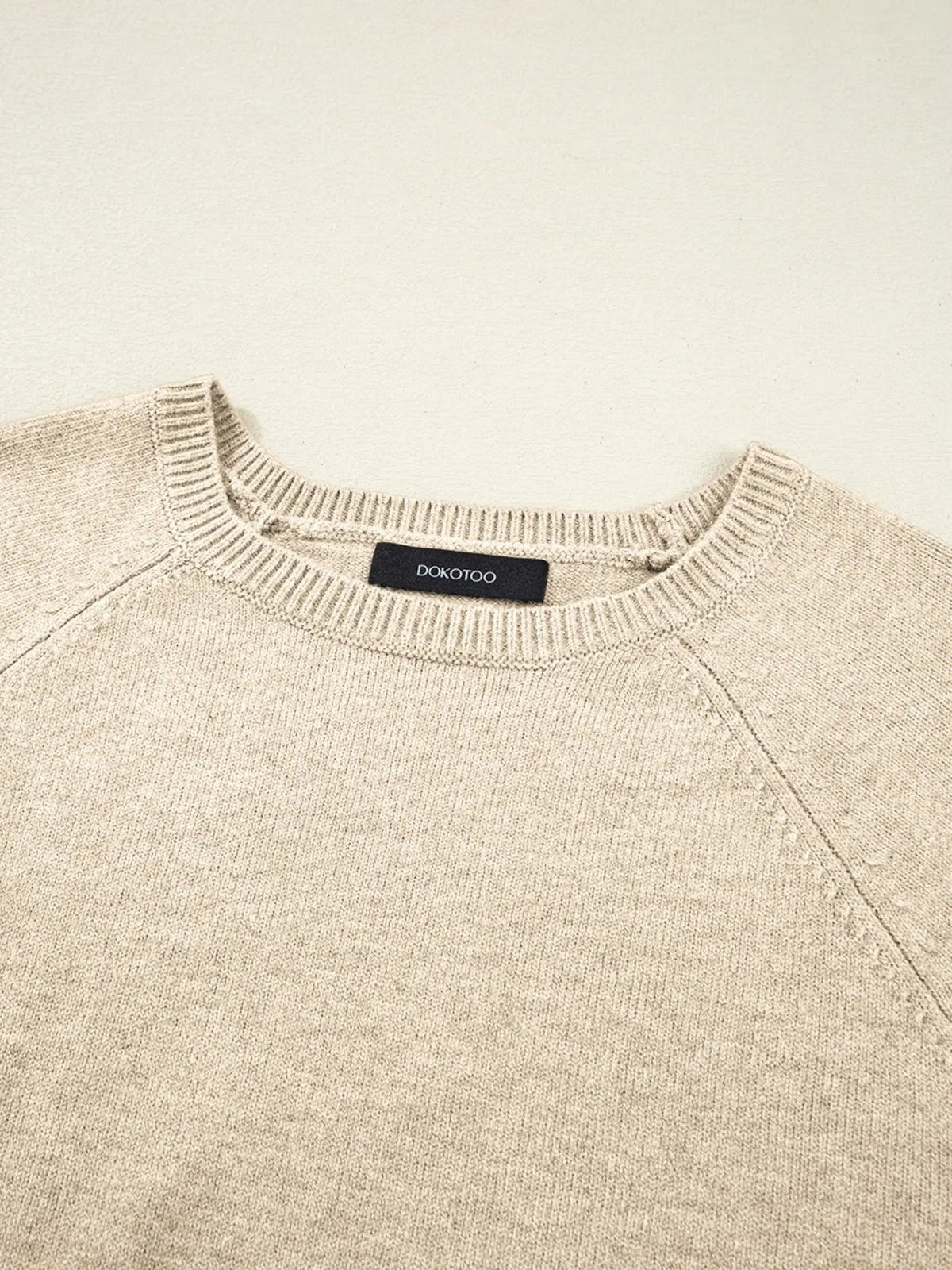 Beige crew neck long sleeve sweater shown flat, featuring a fine-knit construction, ribbed neckline, and visible shoulder seams.