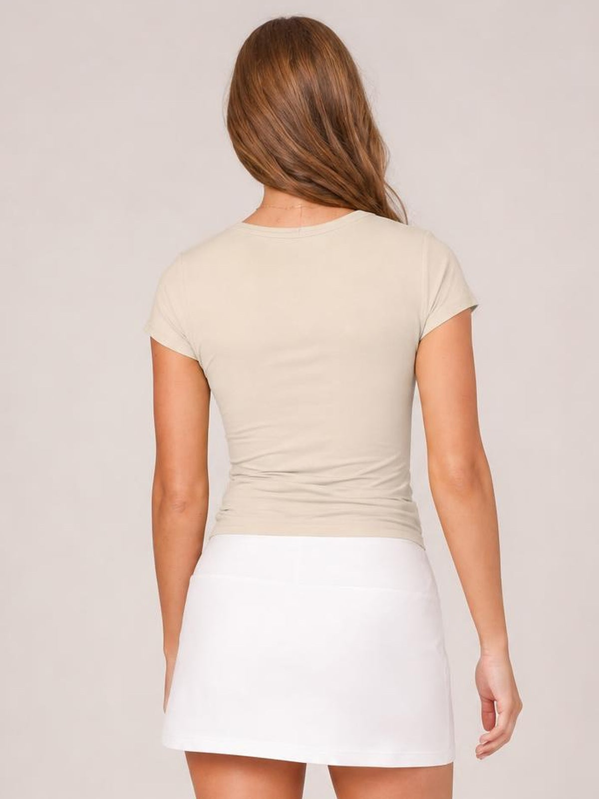 A solid ivory crewneck short sleeve tee with a close-fitting silhouette and regular hem, shown from the back on a standing model.