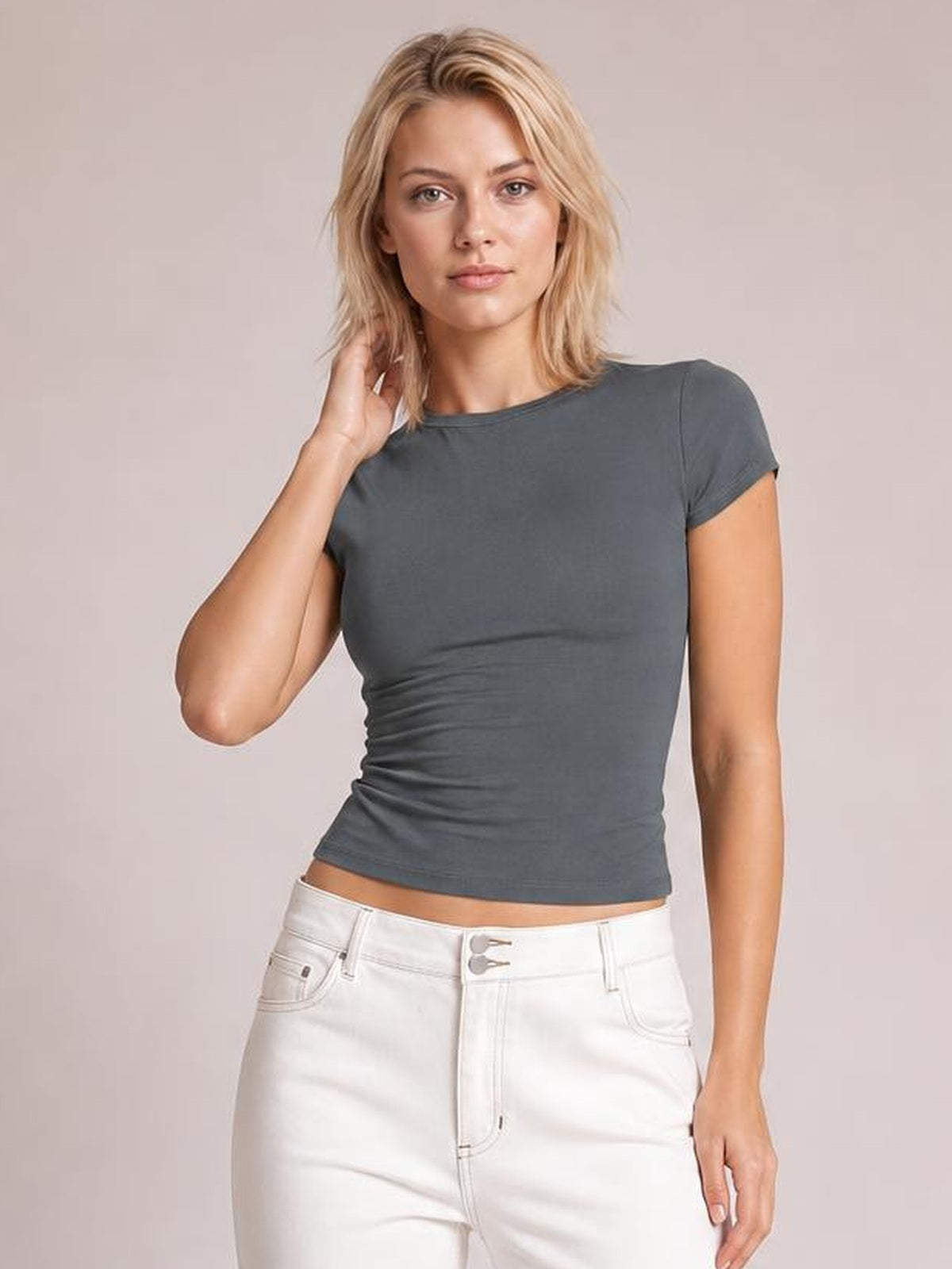 Model touching her hair wears a solid charcoal gray crewneck short sleeve tee with a fitted silhouette and regular-length hem.