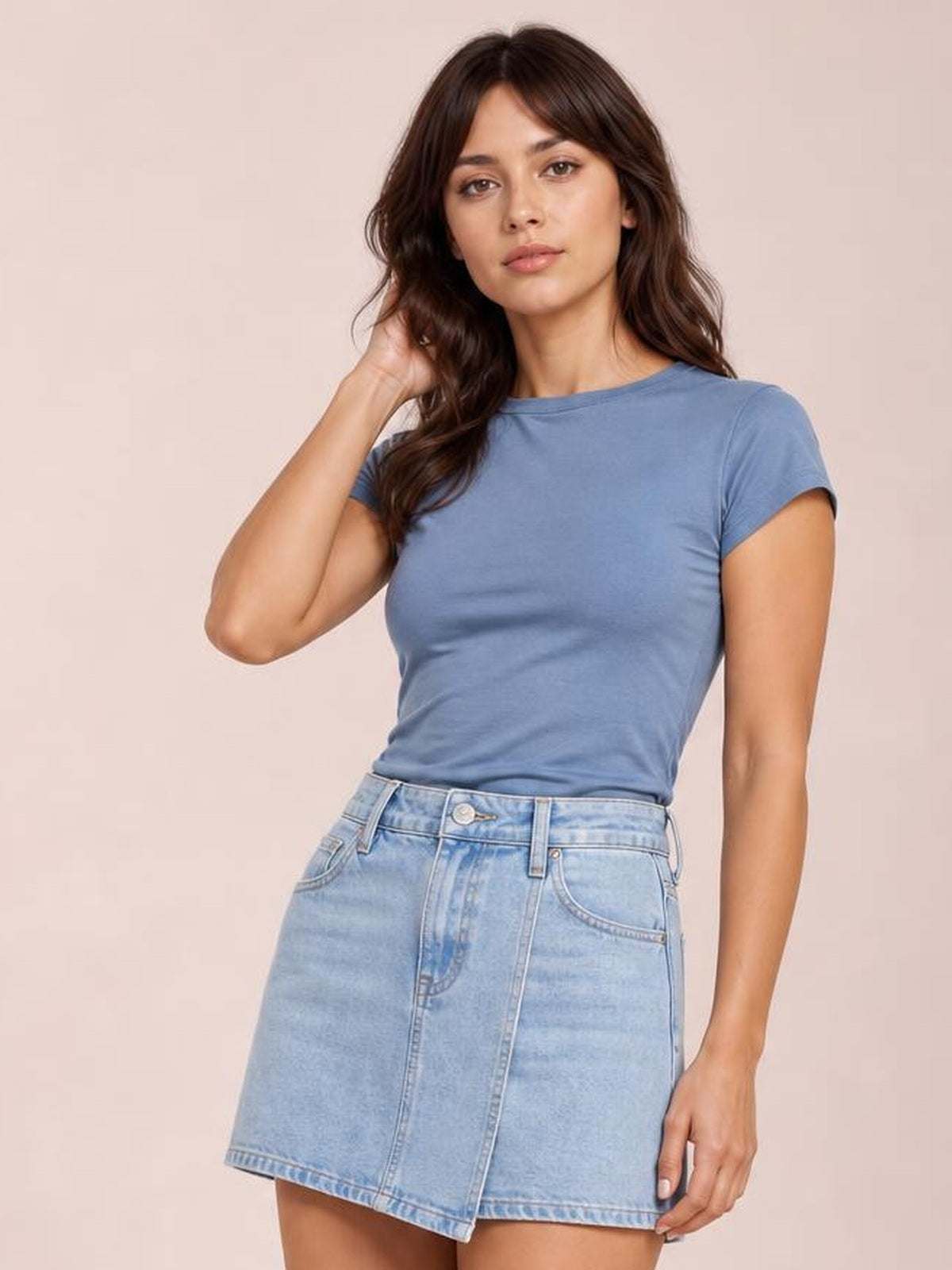 Model poses in a solid blue crewneck short sleeve tee with a regular fit, round neck, short sleeves, and a casual untucked silhouette.