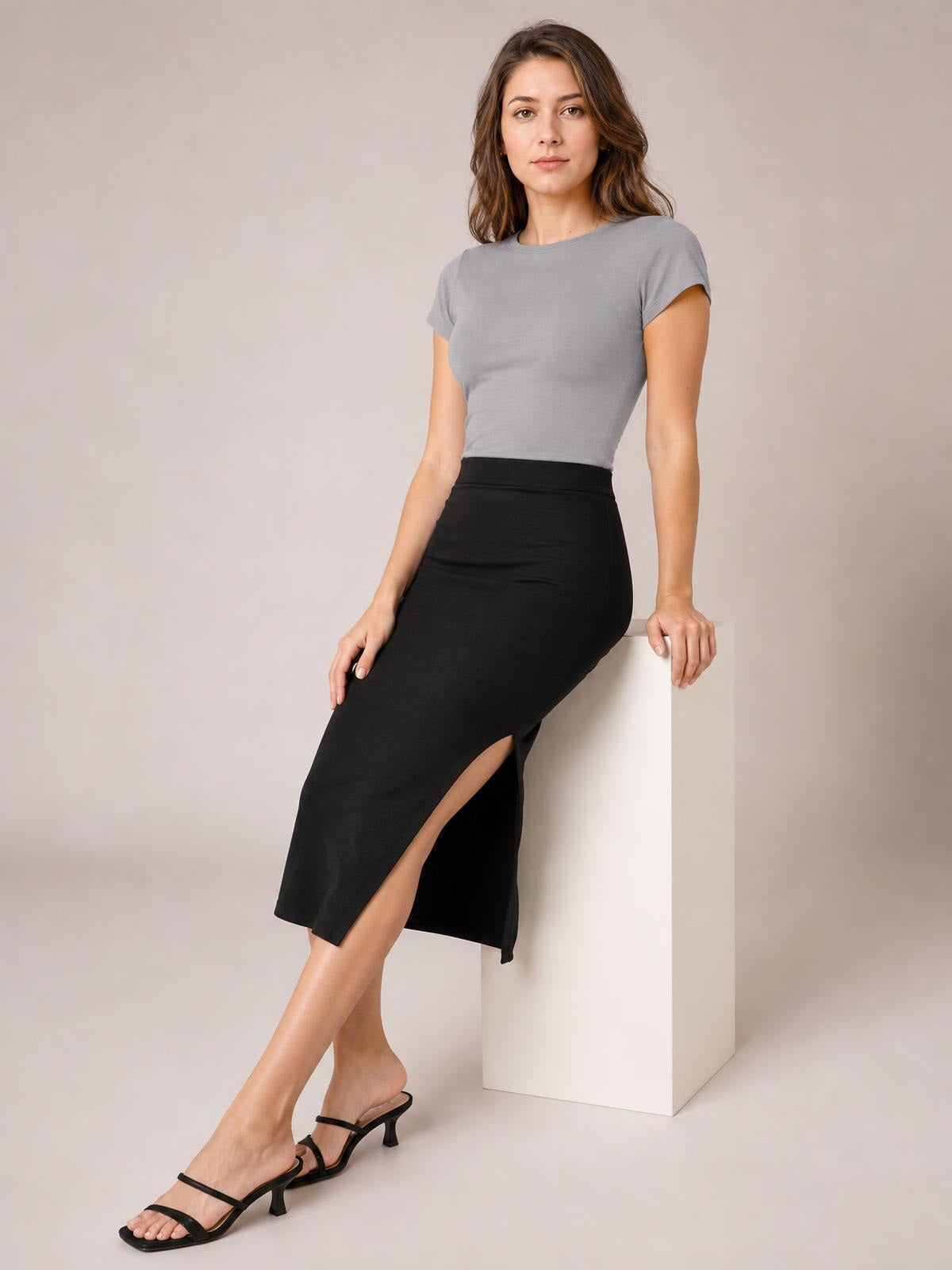 Model seated in a gray solid Crewneck Short Sleeve Tee with a round neckline, regular fit, short sleeves, and a smooth casual silhouette.