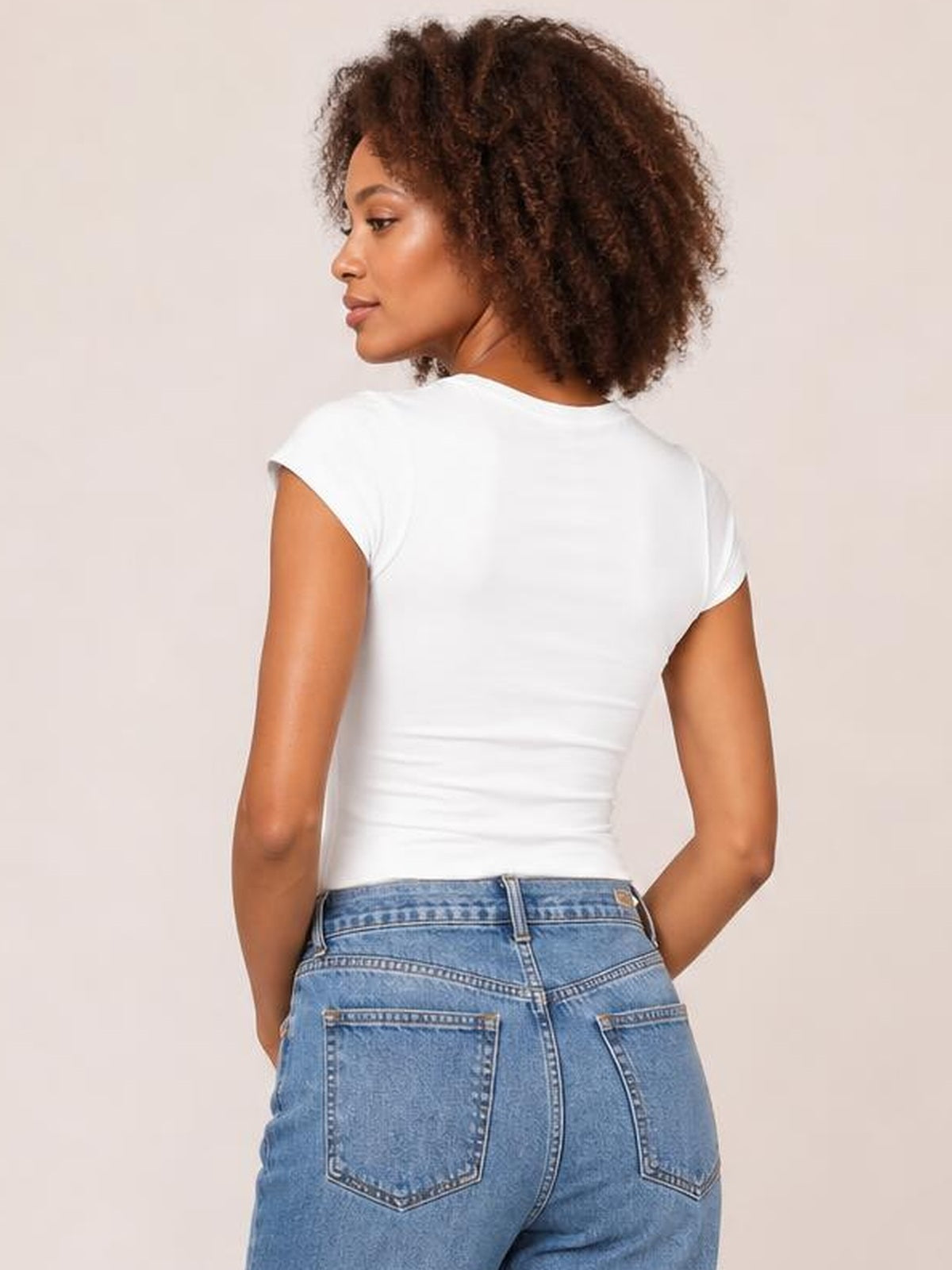 A model looks over her shoulder in a solid white crewneck short-sleeve tee with a close-fitting silhouette and regular-length hem.