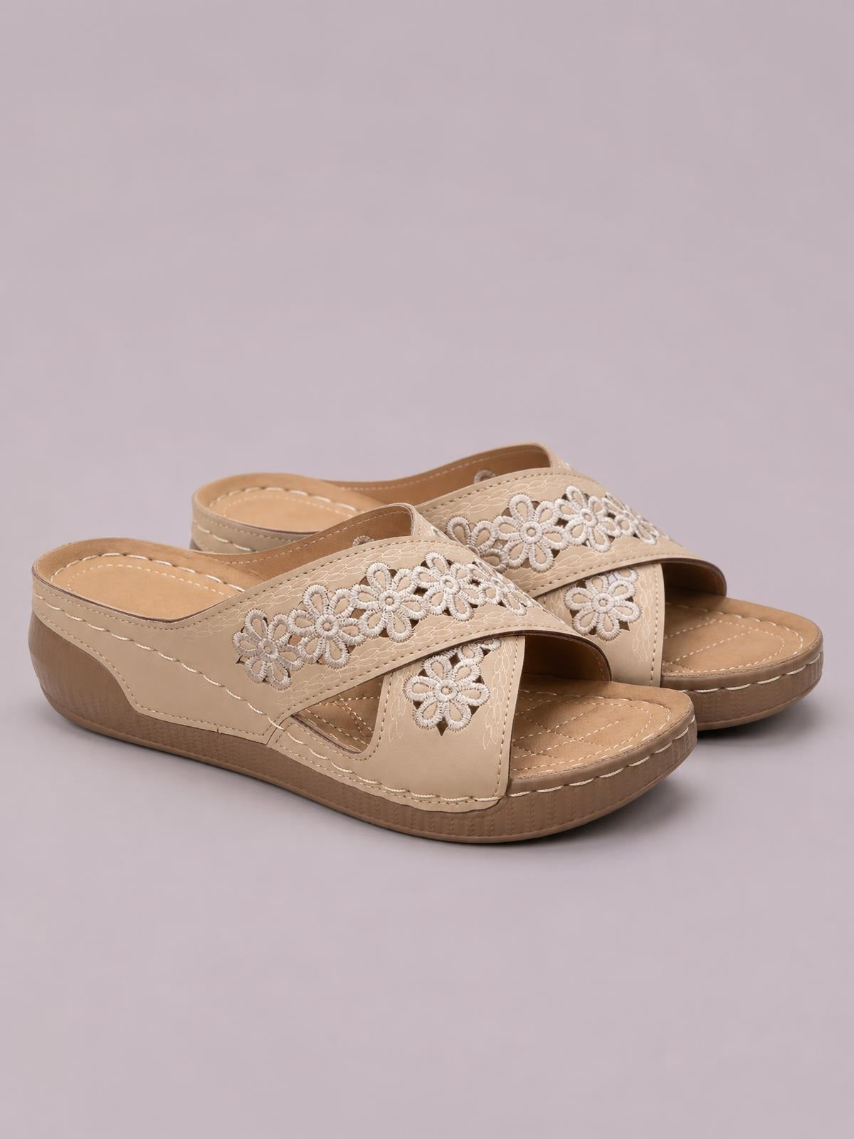 Beige crisscross flower wedge sandals feature open toes, floral-embroidered straps, stitched construction, and comfortable low wedge heels.