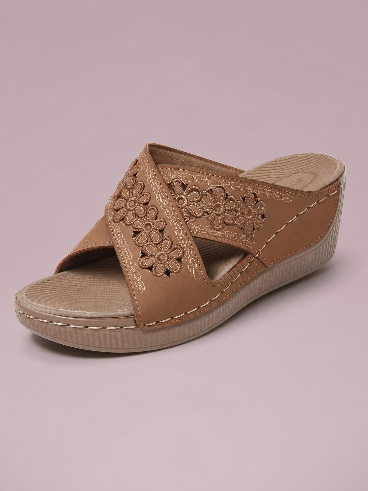 Tan crisscross wedge sandal with open toe, floral-embroidered straps, contrast stitching, textured footbed, and a low platform wedge sole.
