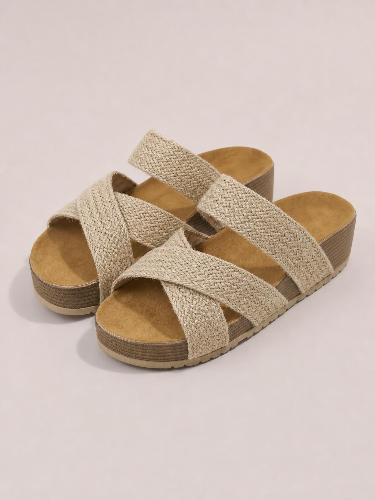 Beige crisscross open-toe platform sandals with wide woven straps, cushioned footbeds, and textured flat platform soles.