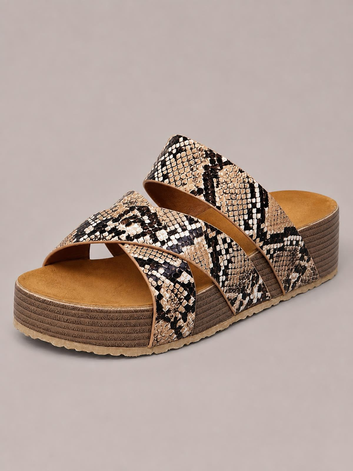 Crisscross open-toe platform sandals feature broad snakeskin-patterned straps in black, cream, and tan over a layered textured sole.