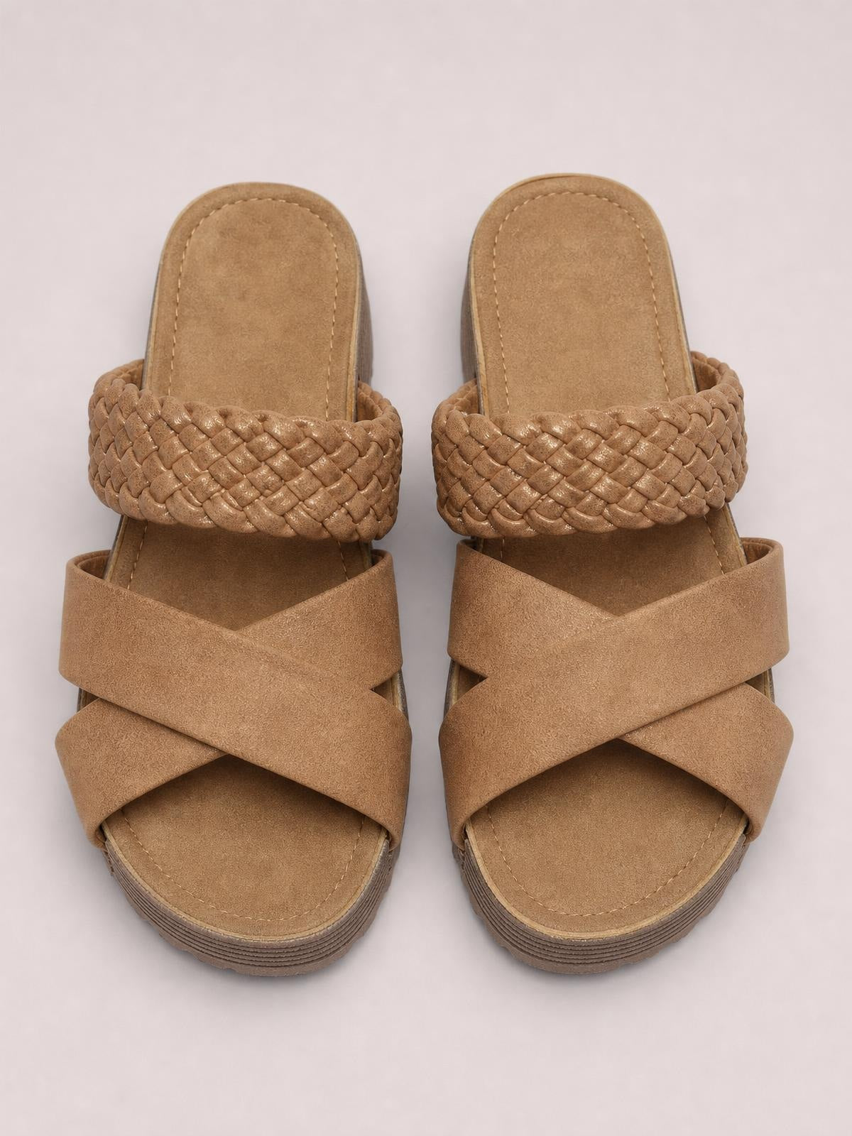 Tan open-toe platform sandals feature wide crisscross straps, braided woven upper bands, stitched footbeds, and layered flat rubber soles.