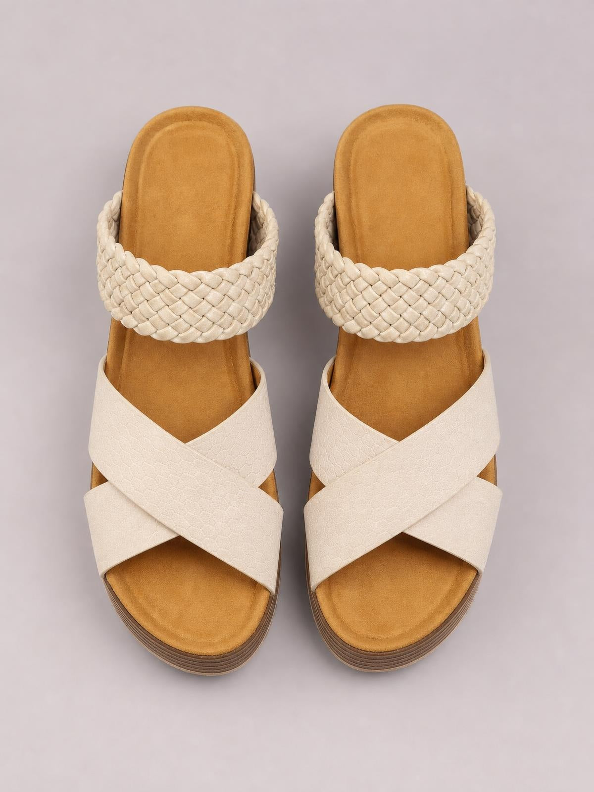Cream open-toe platform sandals feature wide crisscross straps, braided upper bands, cushioned footbeds, and low layered soles.