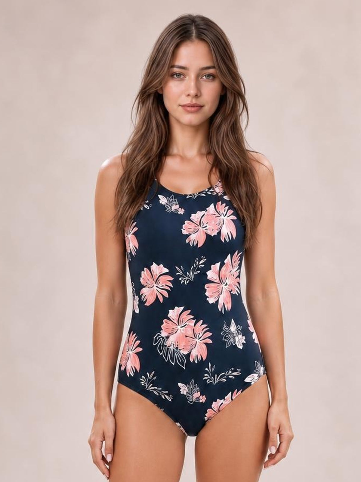 Model standing in a navy floral-print one-piece swimsuit with a round neckline, crisscross front detail, and sleek fitted silhouette.