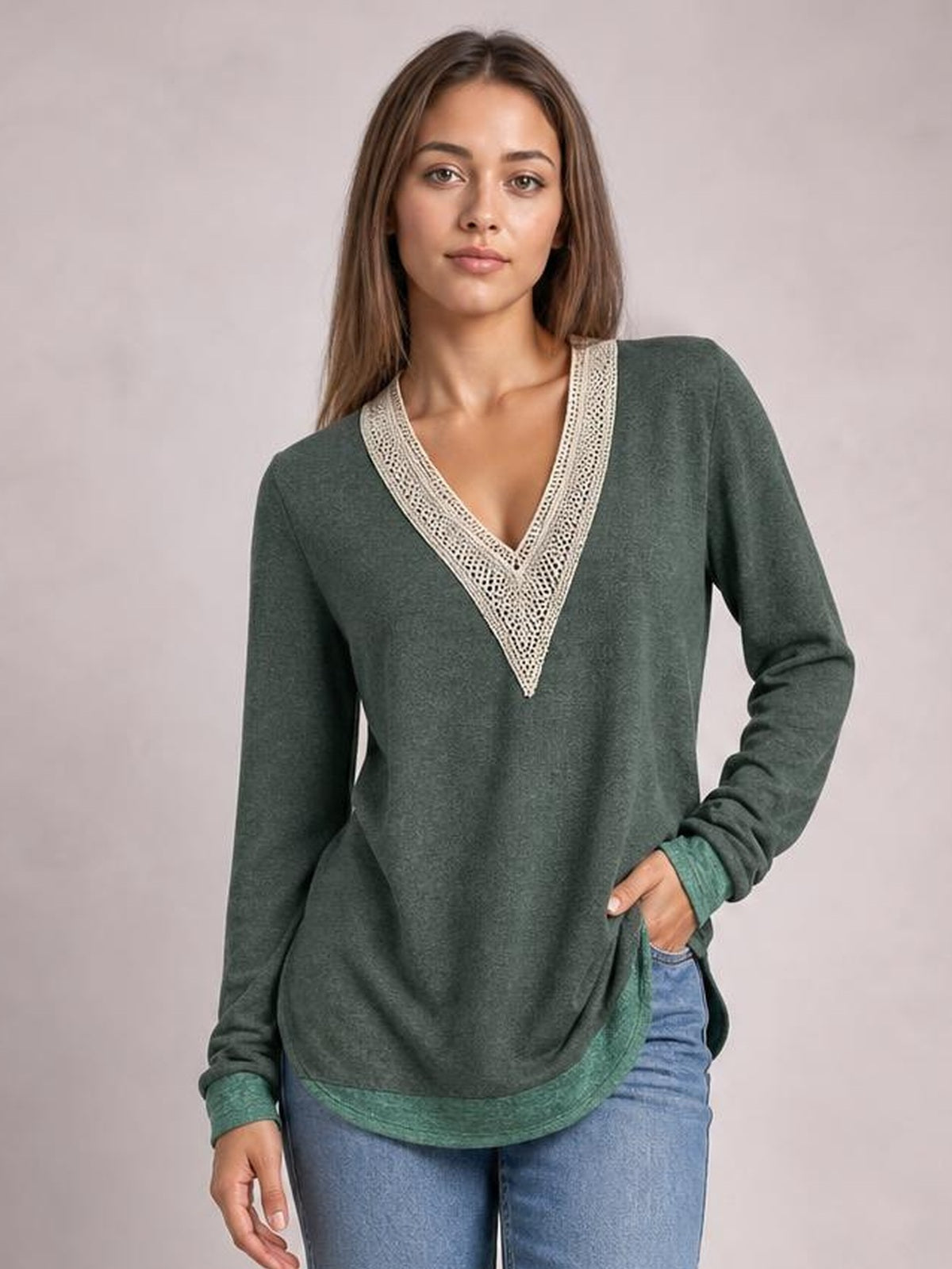 Model poses in a dark green long-sleeve T-shirt with a contrasting crochet V-neck trim, relaxed silhouette, and side slit hem.