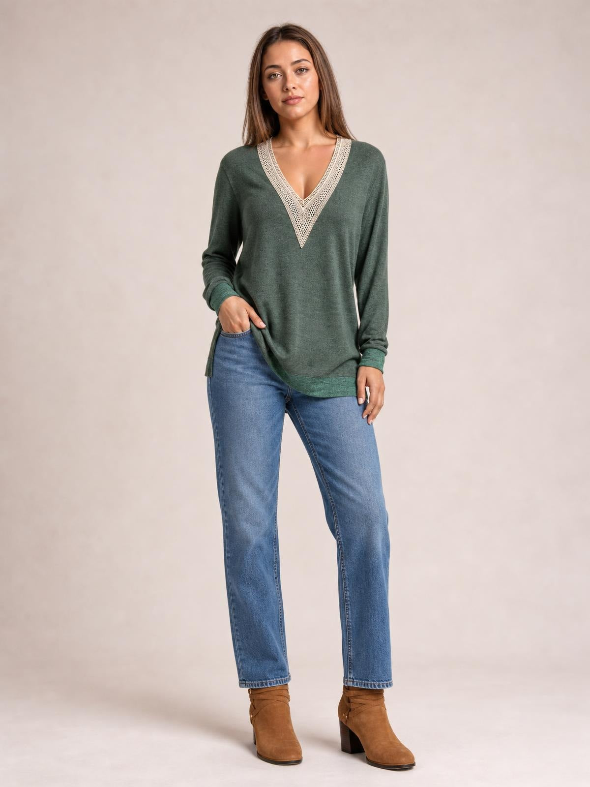 A woman models a relaxed green long-sleeve T-shirt with a crochet-trimmed contrast V-neck and side slit hem, standing with one hand at her hip.