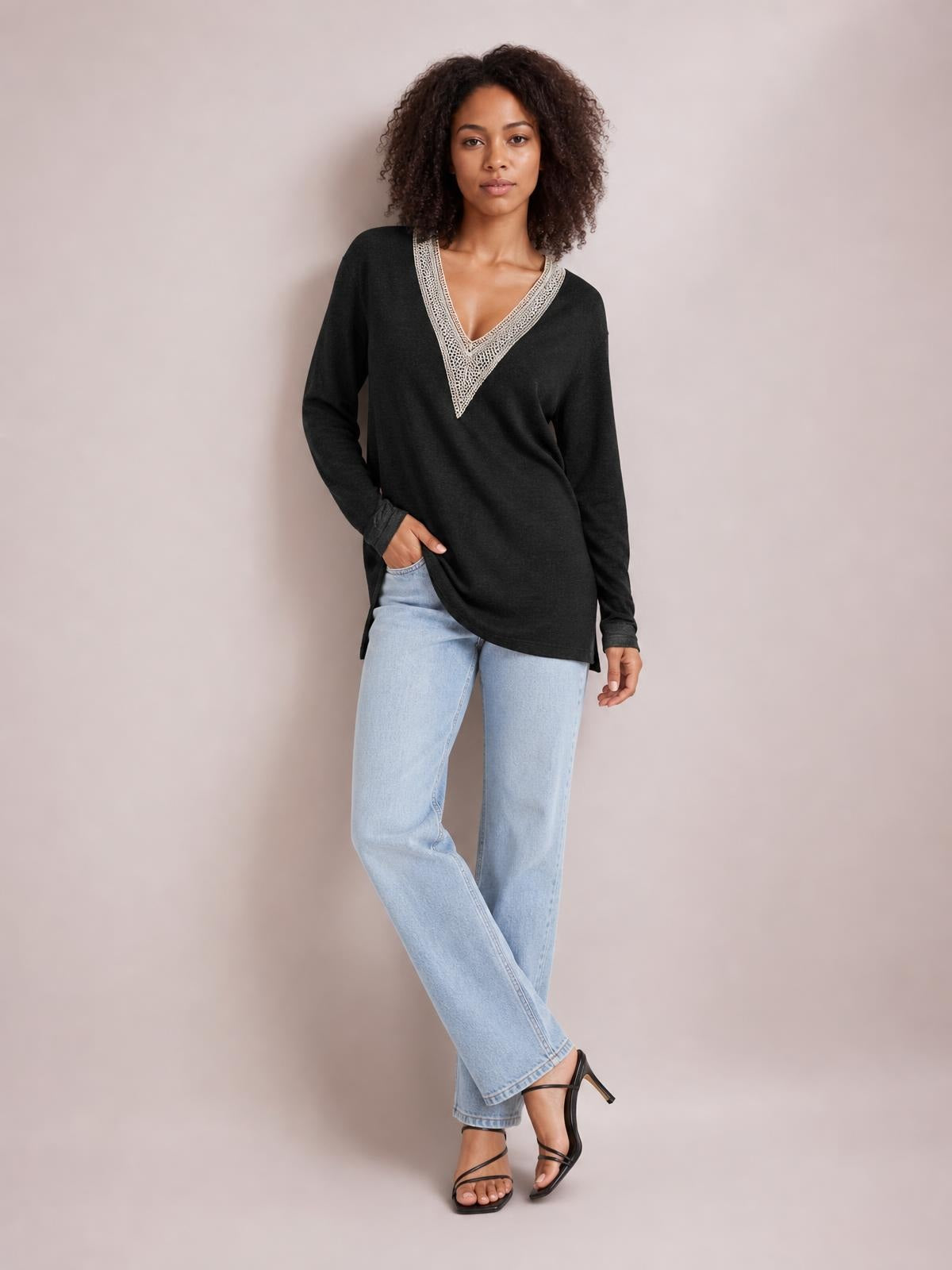 Model poses in a black long-sleeve slit T-shirt with a contrasting crochet-trimmed V-neck and relaxed, slightly oversized silhouette.