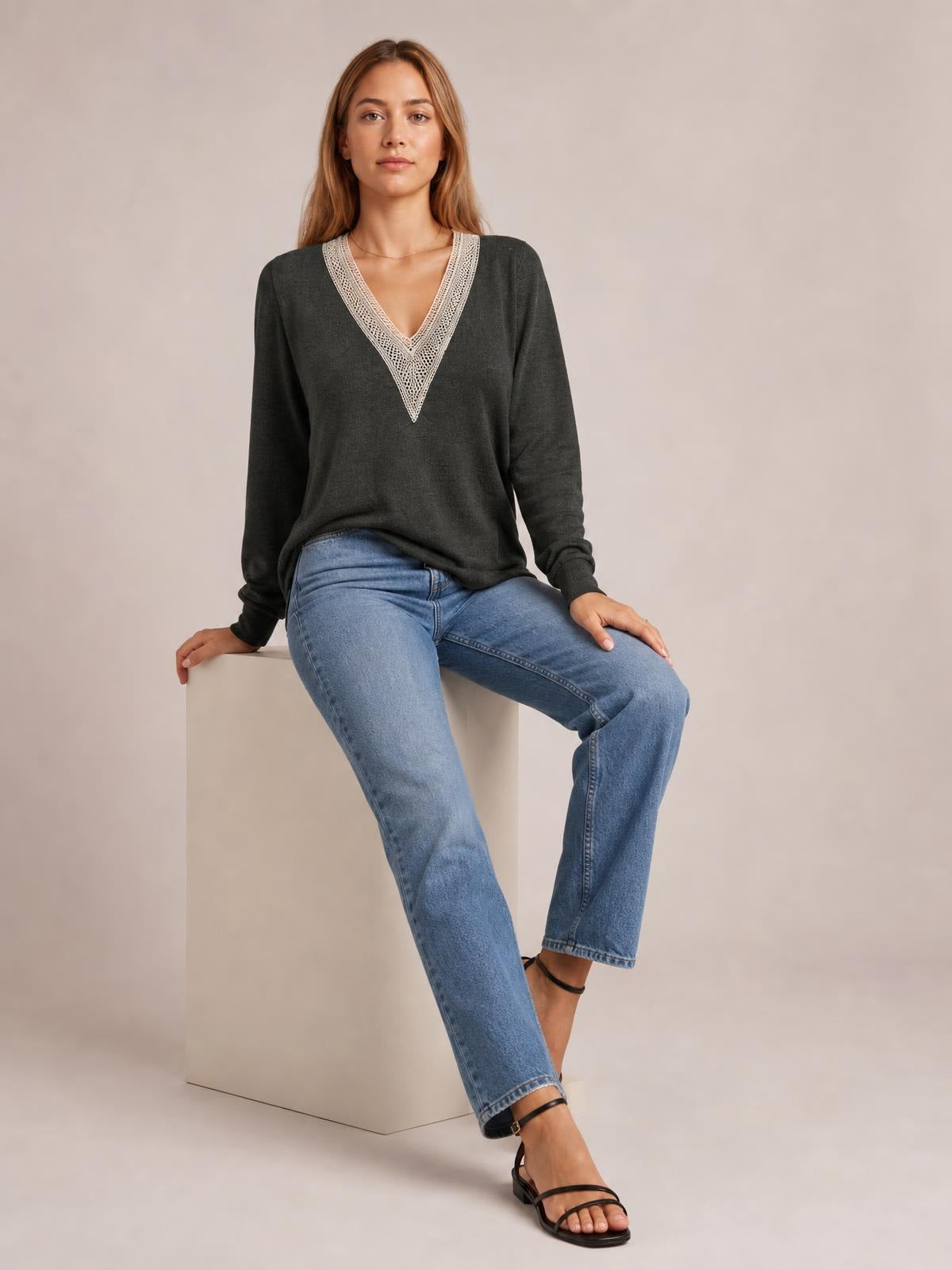 A model sits in a relaxed charcoal long-sleeve T-shirt with a contrasting crochet-trimmed V-neck and easy straight silhouette.
