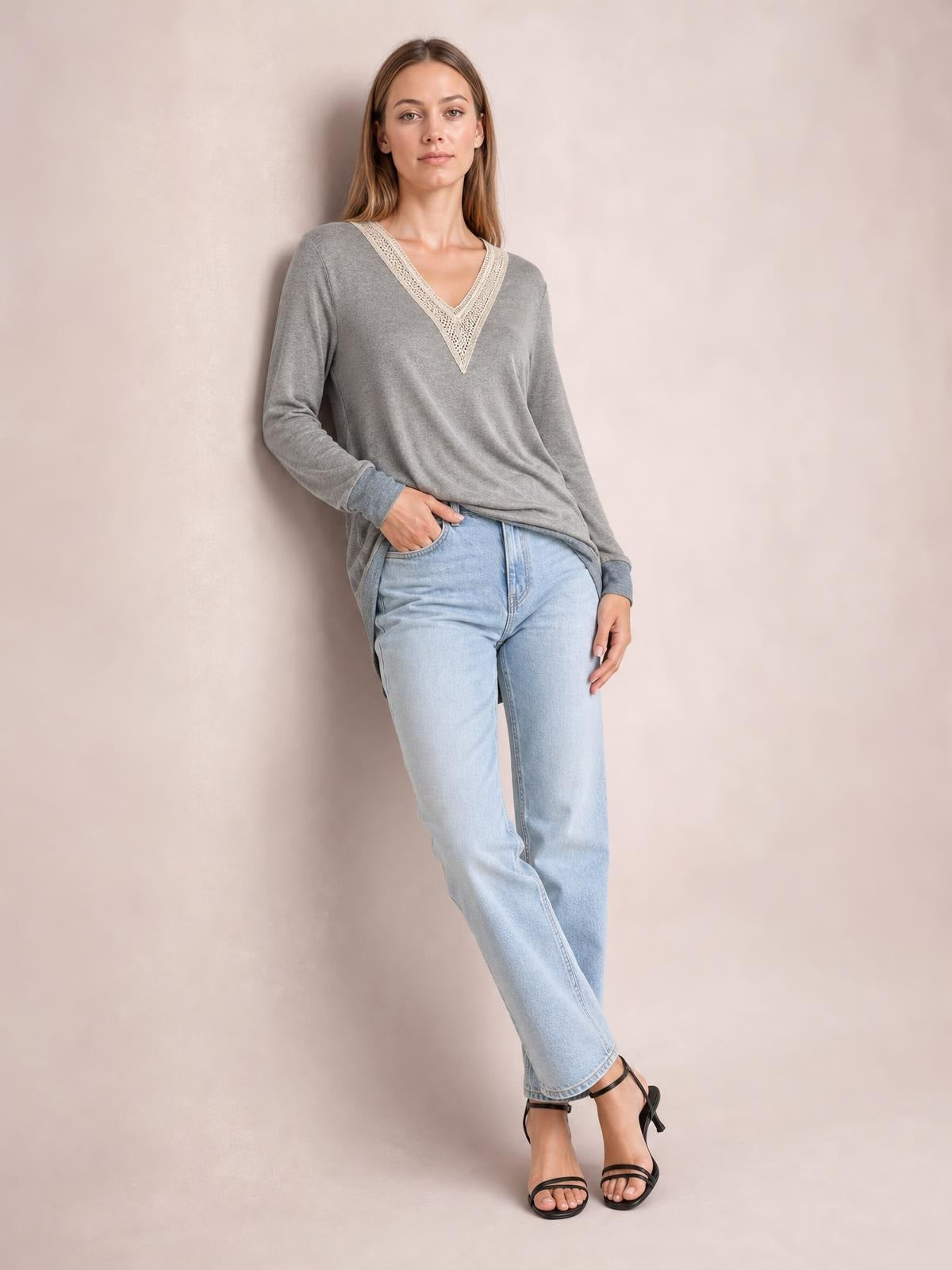 Model poses in a relaxed gray long-sleeve T-shirt with a contrasting crochet V-neck, slightly loose silhouette, and visible side slit.
