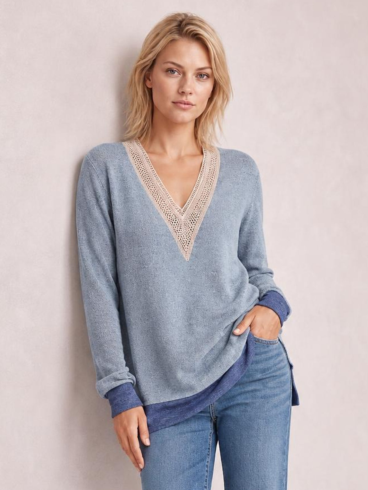 Model poses with one hand in her pocket wearing a light blue long-sleeve T-shirt with a contrasting crochet V-neck, ribbed cuffs, and side slit hem.