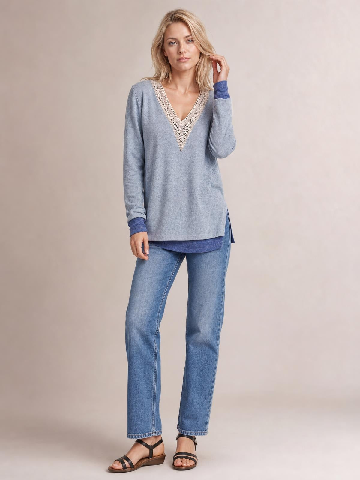 A model wears a blue-gray crochet contrast V-neck long-sleeve T-shirt with a relaxed silhouette and side slit, touching her hair.