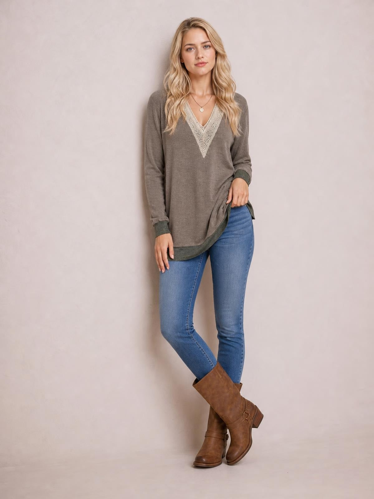 A model poses in a taupe crochet contrast V-neck long sleeve slit T-shirt with a relaxed tunic silhouette and darker ribbed cuffs.