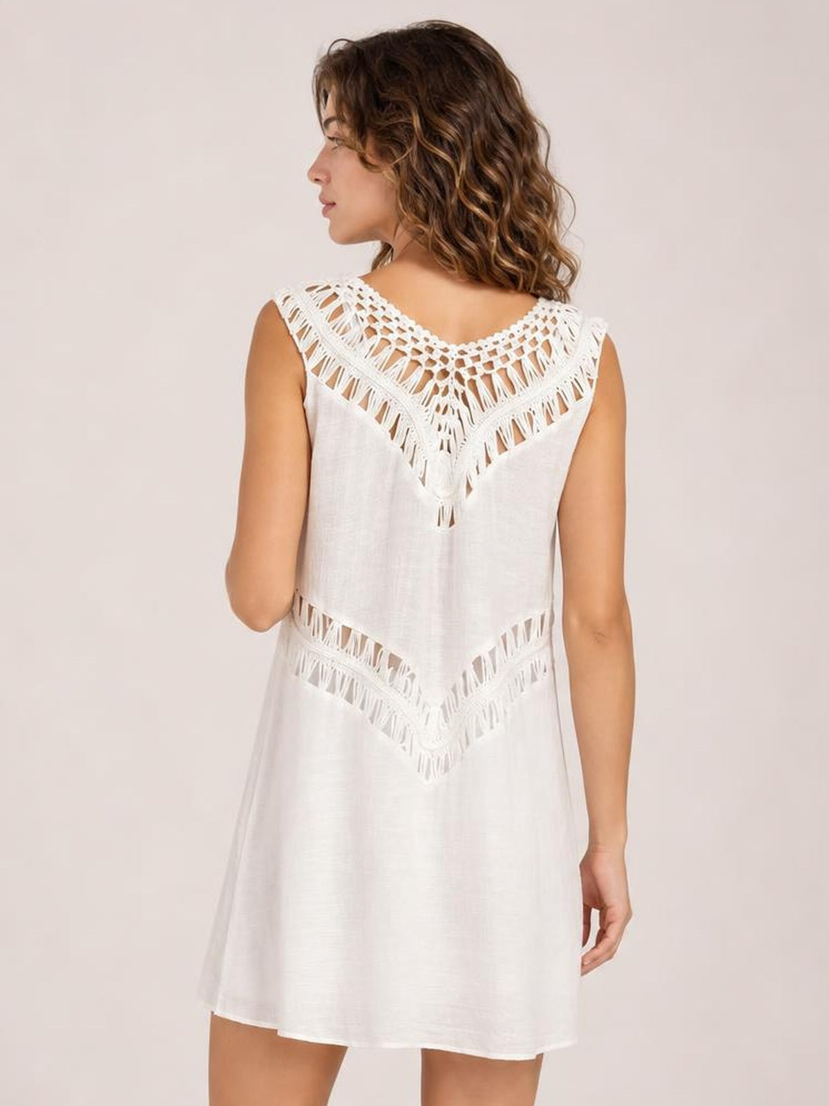 Model shown from the back in a white beach cover up dress with crochet cutout panels, sleeveless design, and a relaxed A-line silhouette.